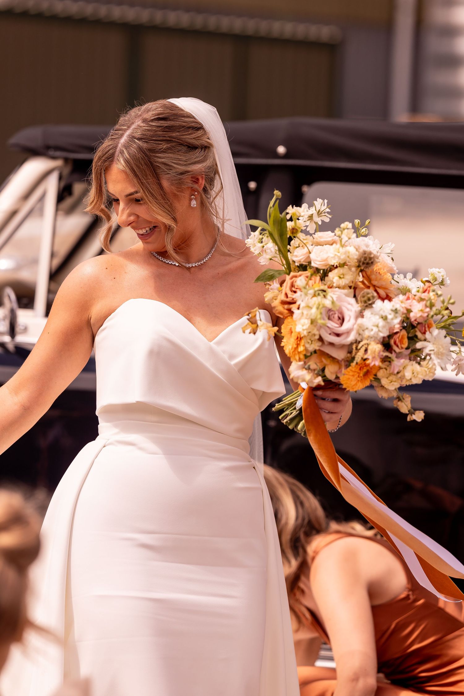 Bride in white dress holding a romantic pastel floral bouquet.