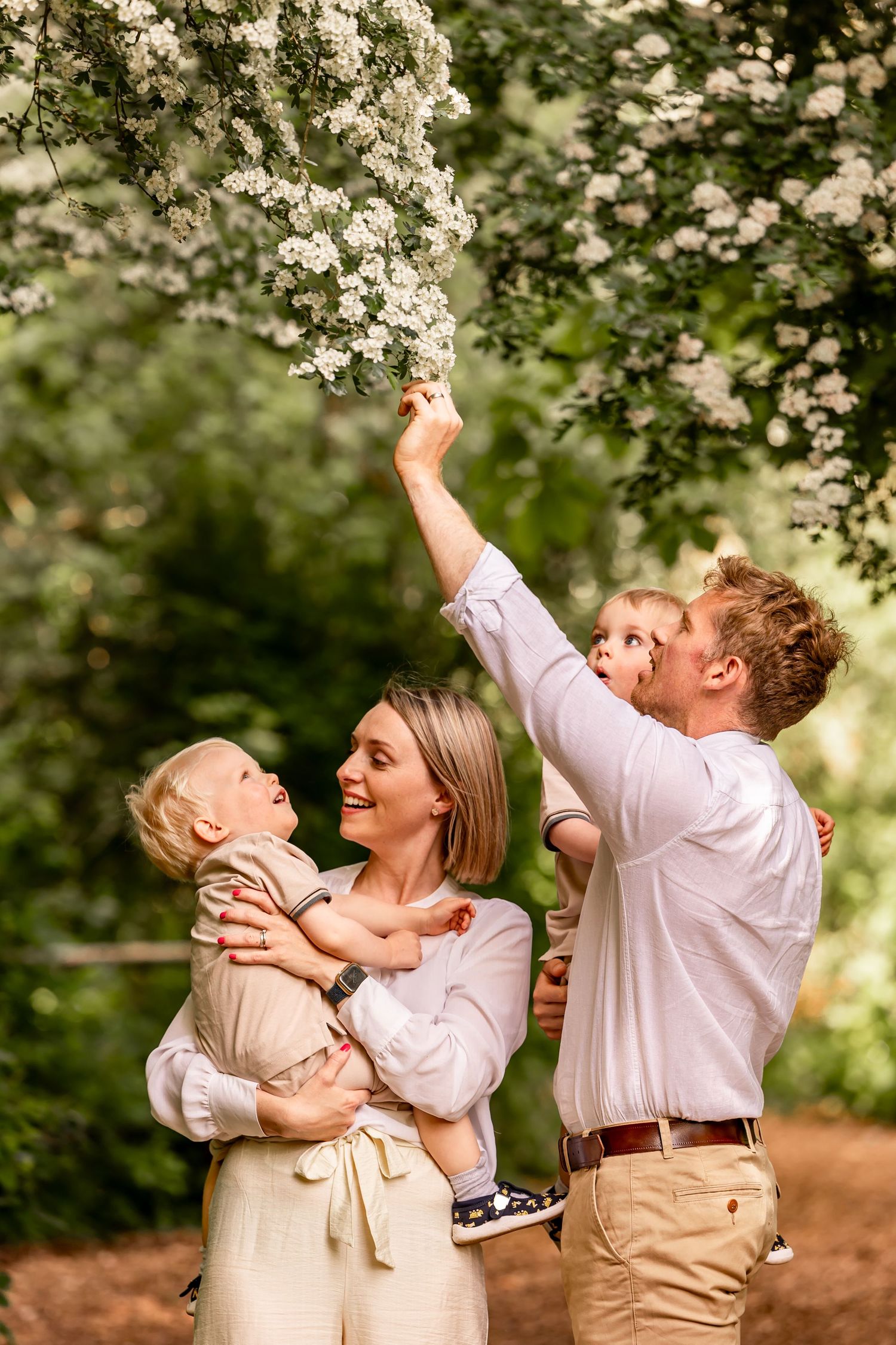 Family enjoying a lighthearted moment together under flowering tree branches.