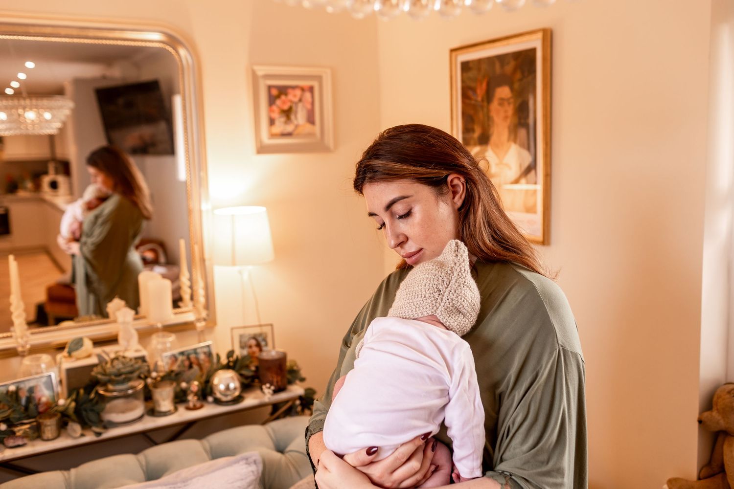 Intimate moment of parent holding baby in warmly lit room.