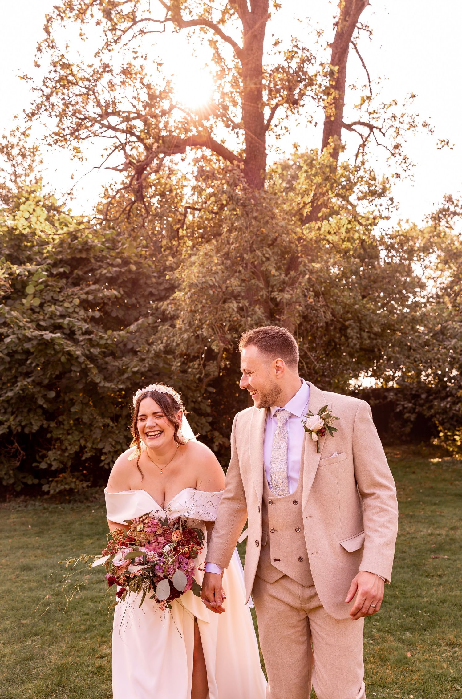 Sunset wedding portraits in an orchard with warm golden light filtering through trees.