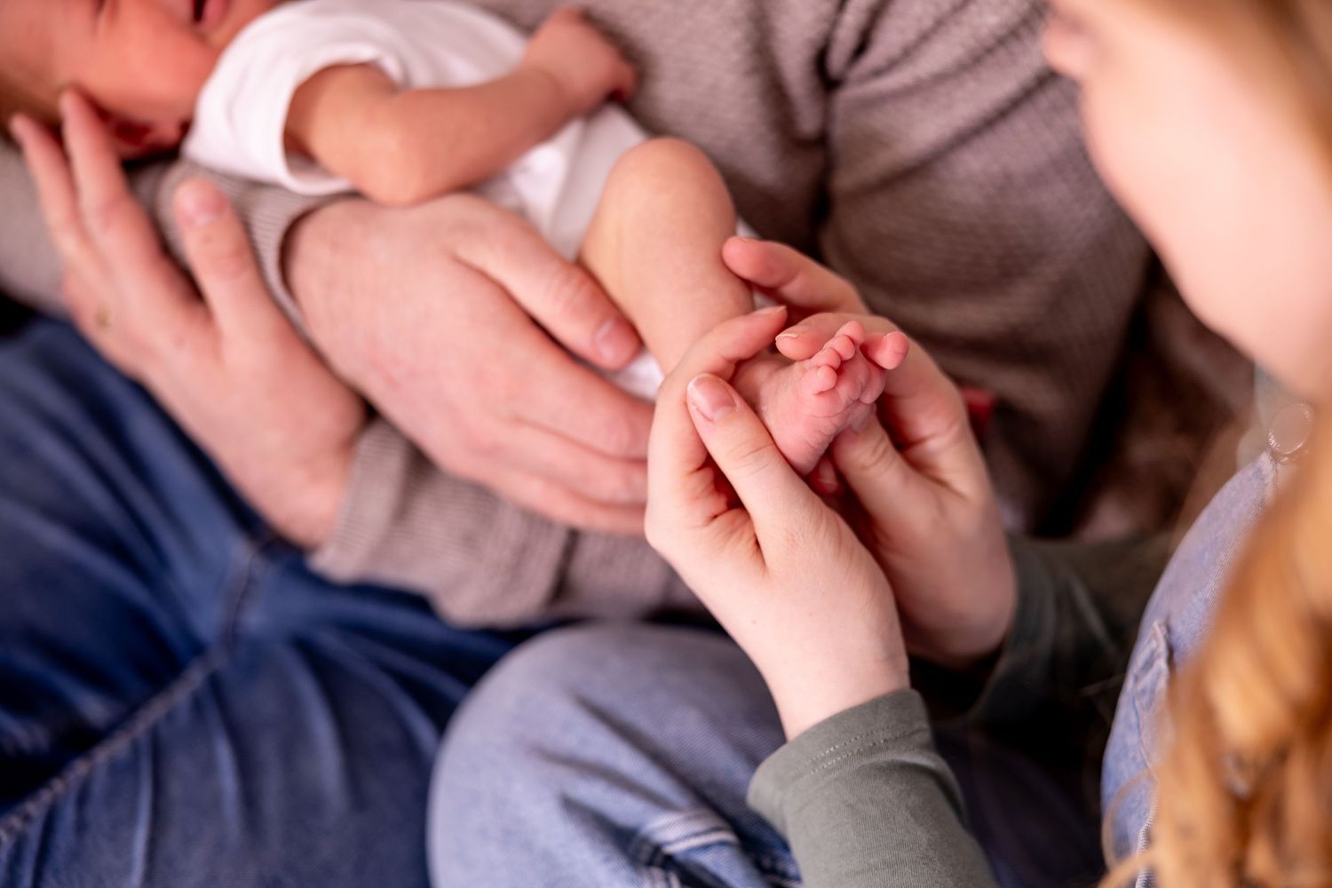 Close-up shot of hands holding a newborn baby's tiny fingers with gentle care.