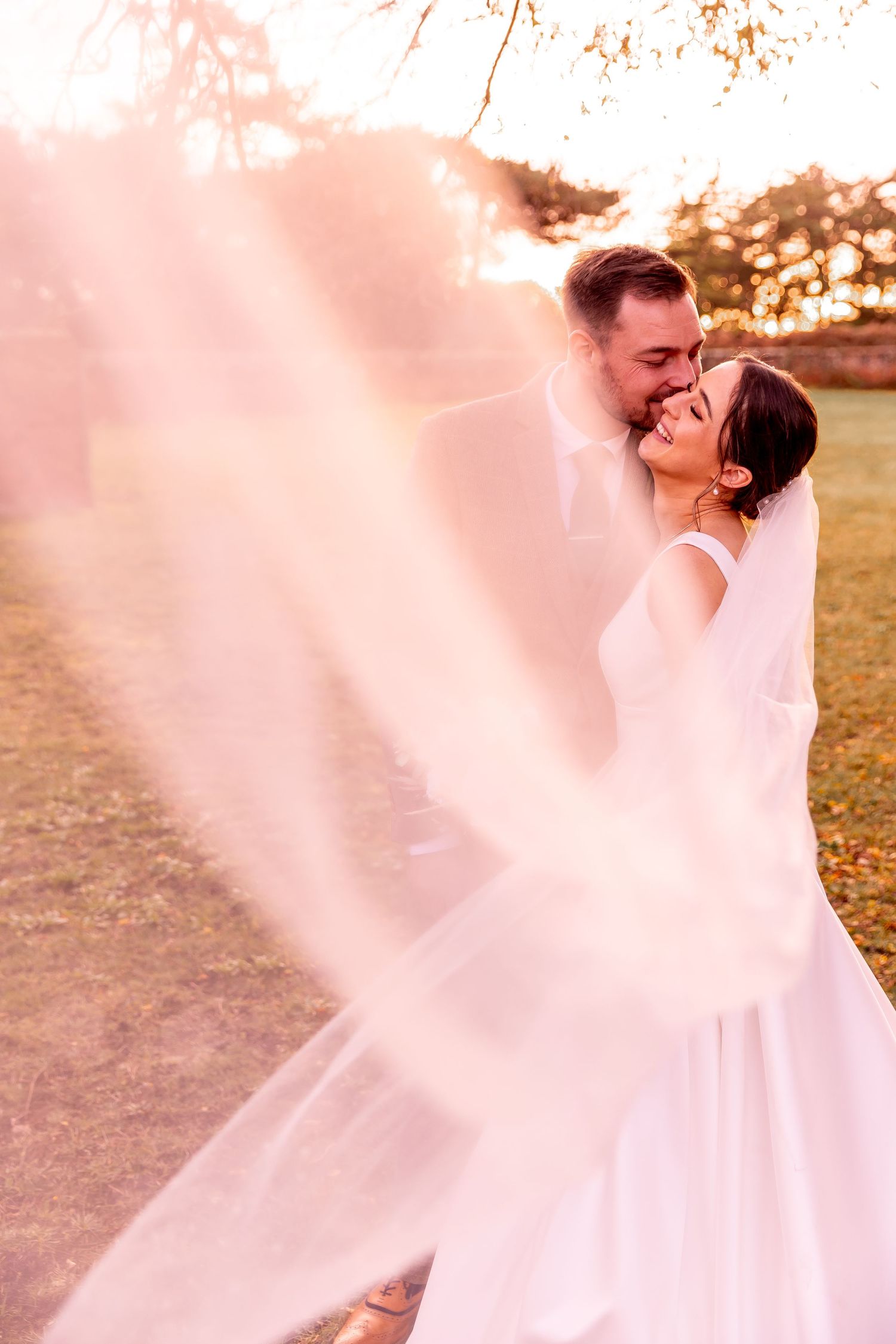 Ethereal wedding photos show couple dancing with flowing white dress in soft sunset light.