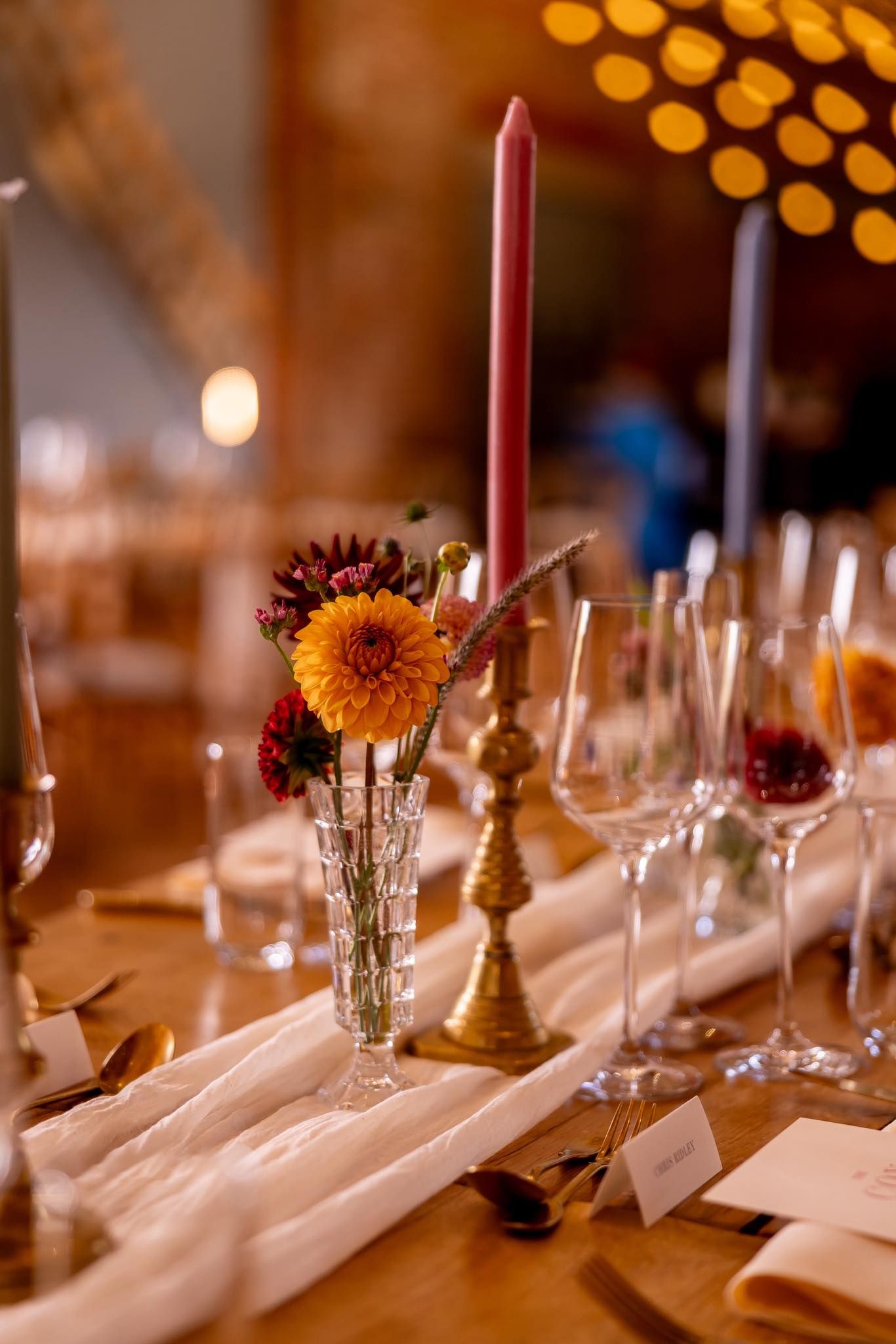 Elegant wedding reception table with sunflowers, candles and place settings.