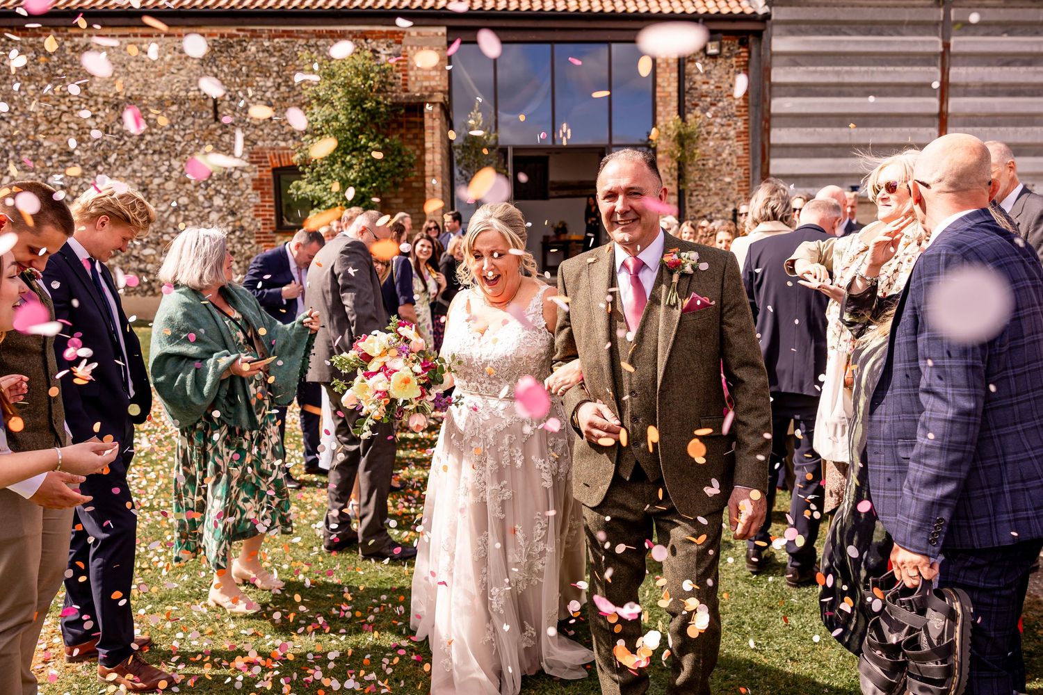 Wedding guests toss flower petals during an outdoor celebration.