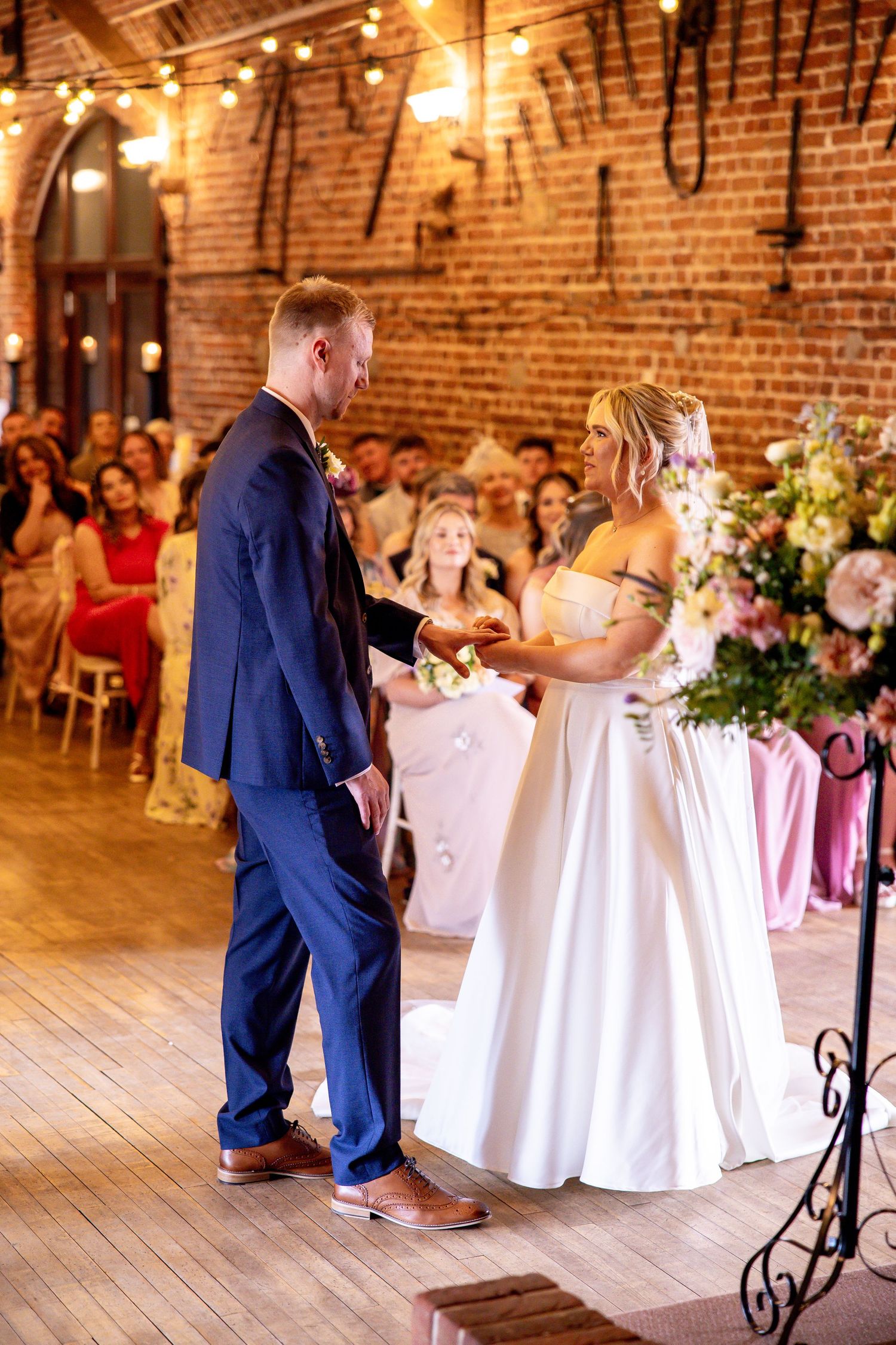 Rustic brick venue interior with elegant white tablescapes and wedding reception decor.