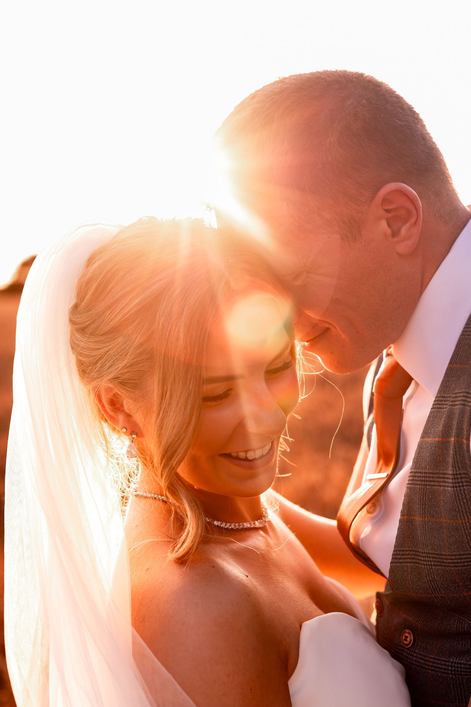 Sunset portrait of newlyweds sharing an intimate moment with golden backlighting.