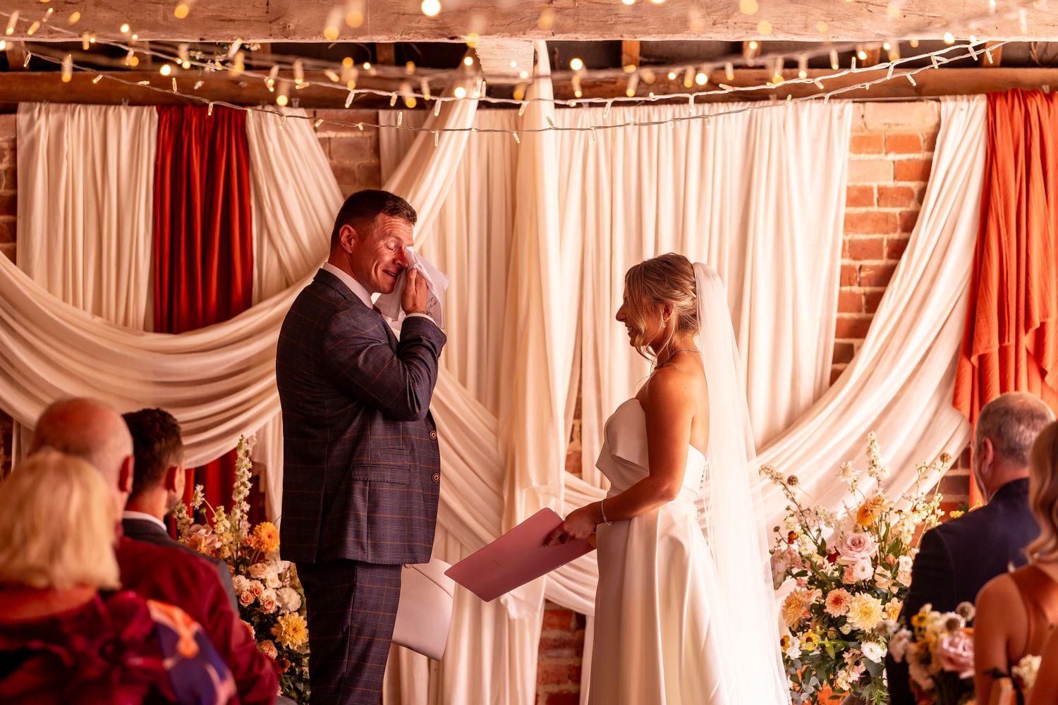 Wedding celebration in a rustic brick venue with string lights and white drapes creating a romantic atmosphere.