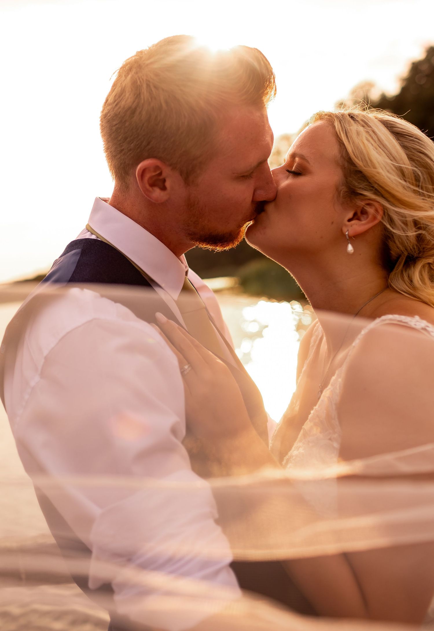Romantic sunset silhouette of newlyweds sharing an intimate moment.