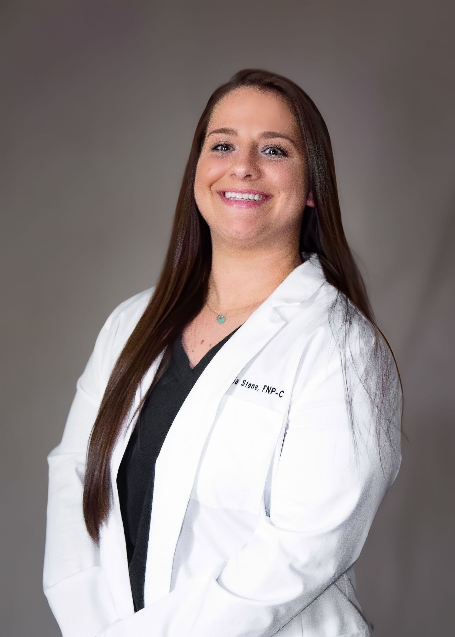 Smiling female healthcare professional in white lab coat with TNP-C credentials, long brown hair, gray background.