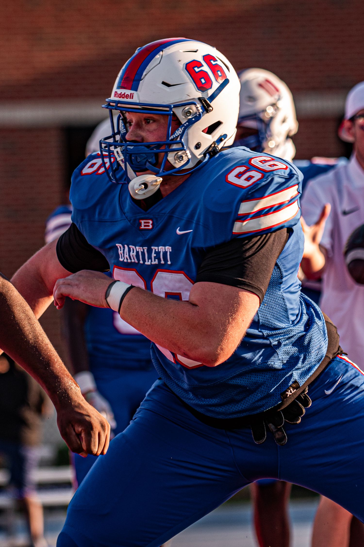 Bartlett football player number 66 in blue uniform blocking during a game.