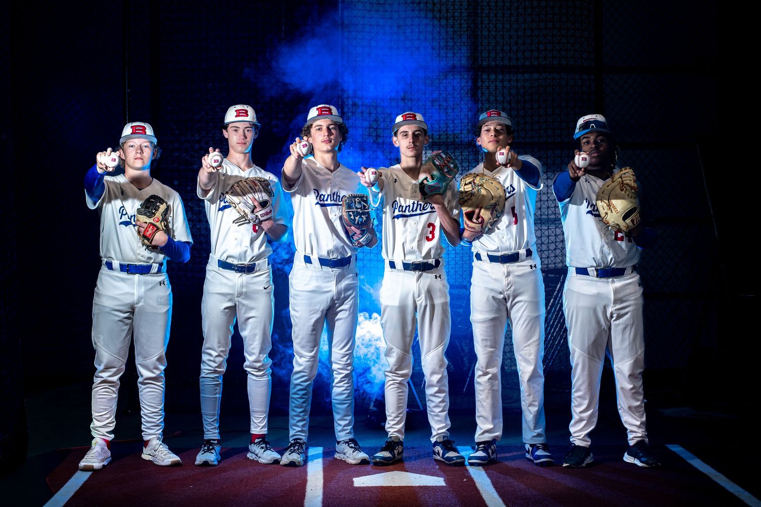 Six baseball players in blue and white uniforms pose dramatically under blue stadium lighting.