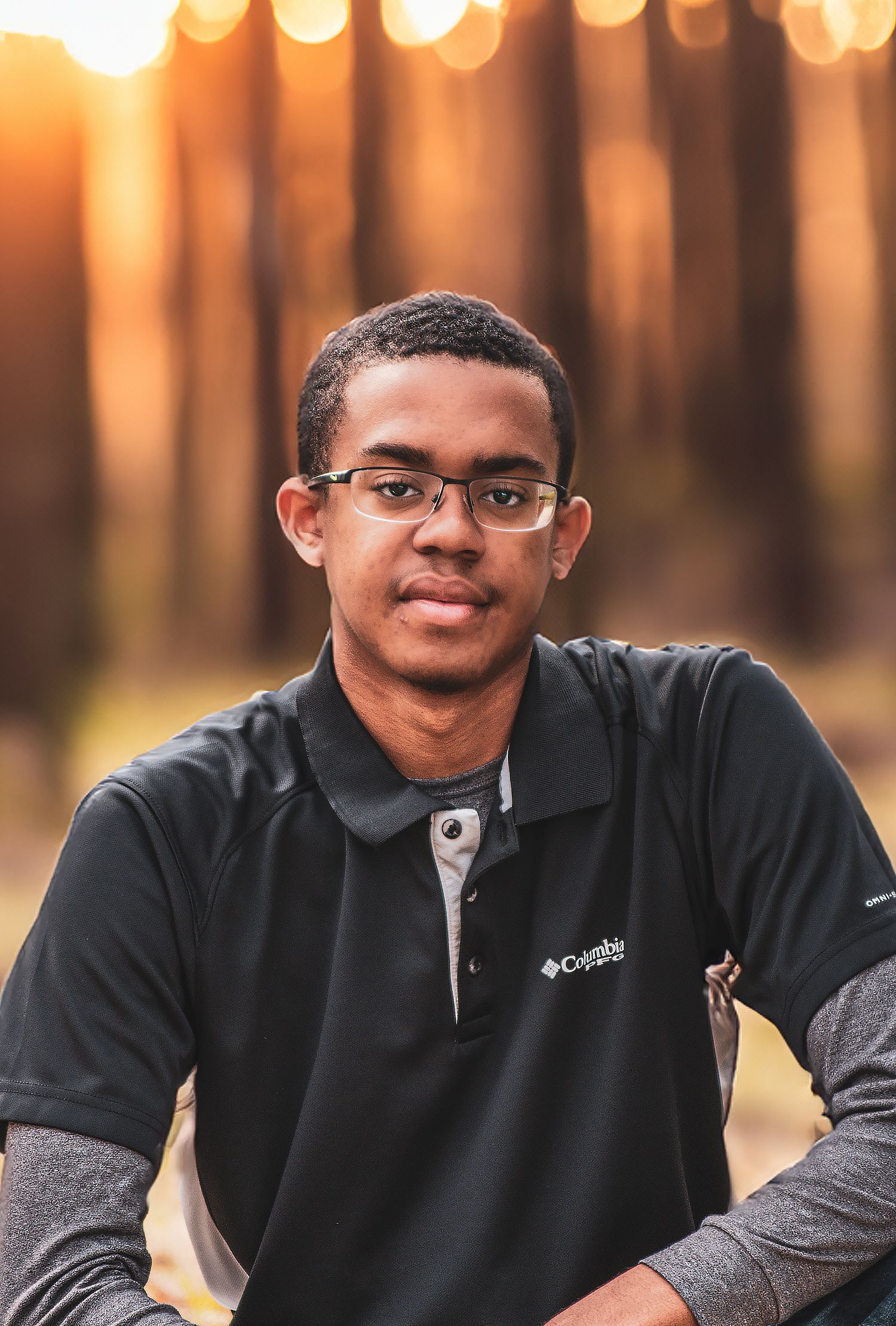 Young man in Columbia polo shirt smiles during golden hour outdoor portrait.