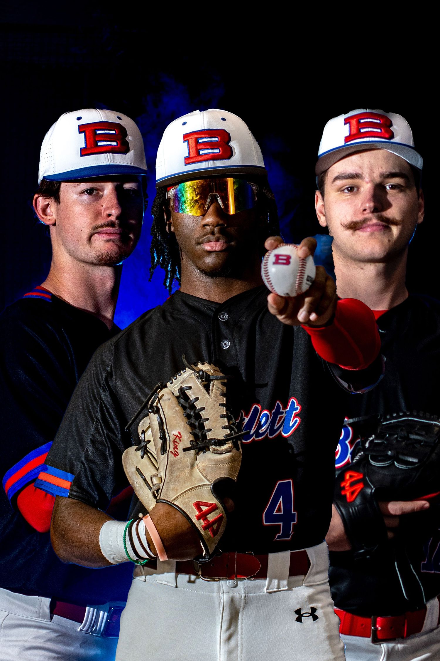 Three baseball players in Bartlett uniforms pose confidently against a dark dramatic background.