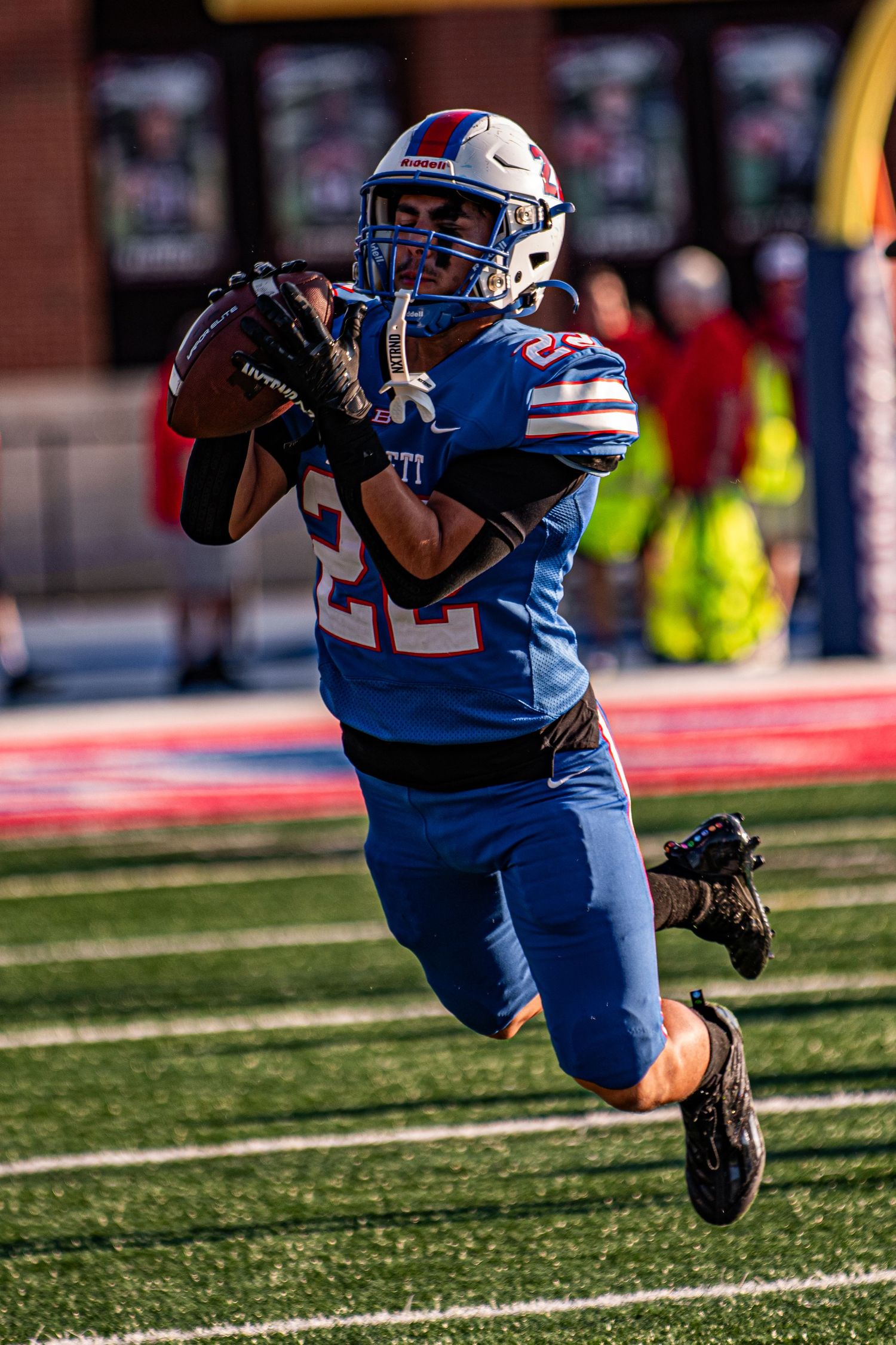 Football player in blue number 22 uniform making an impressive catch during a game.