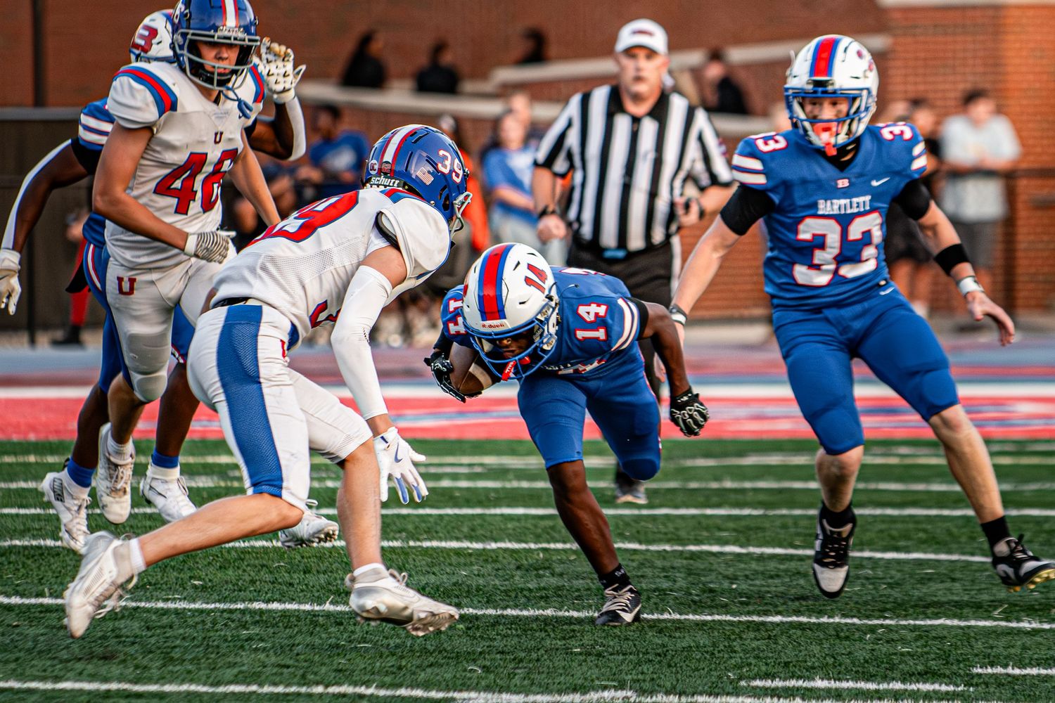 High school football players in blue and white uniforms during an intense game play.