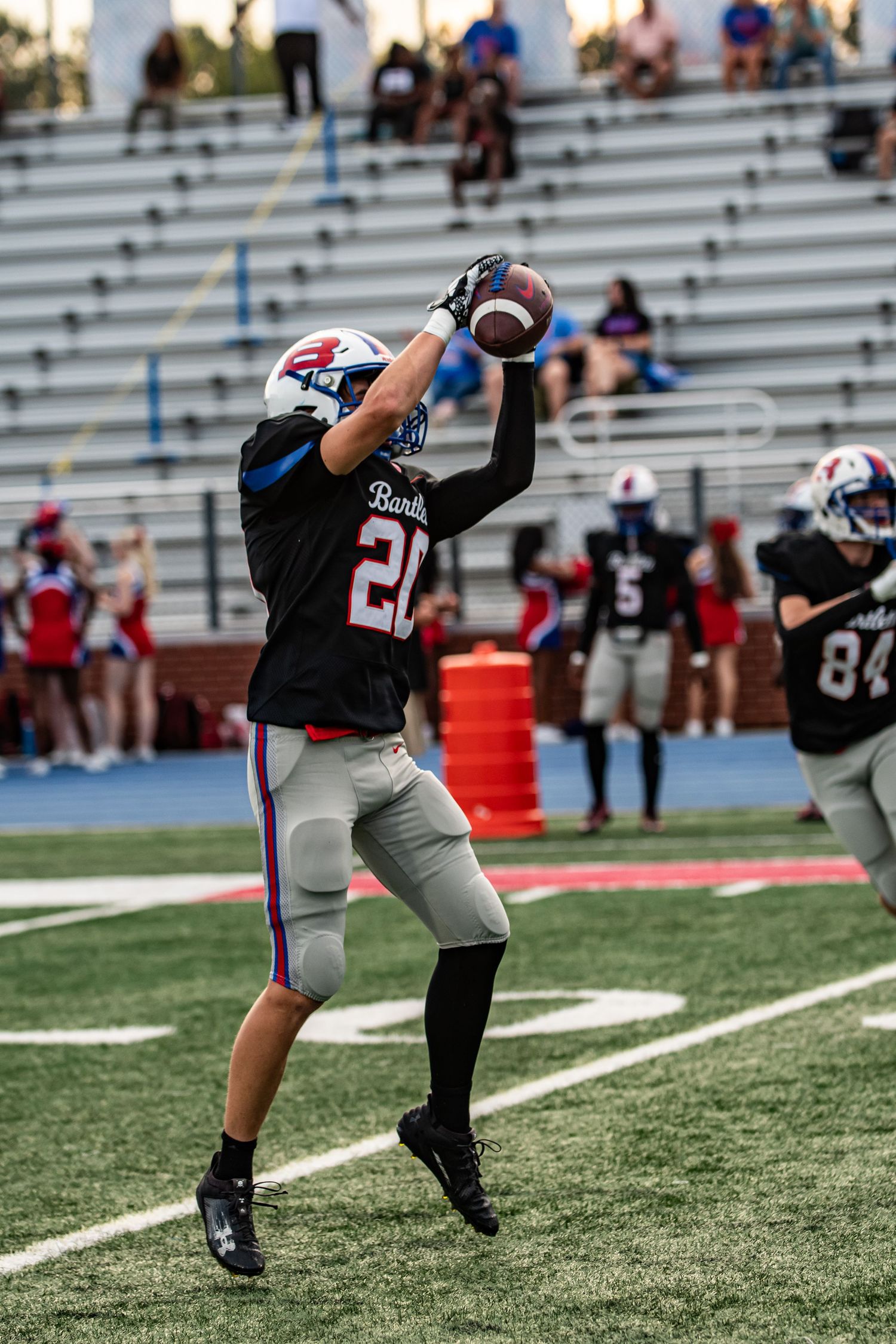 Football player in black jersey catching pass during high school game.