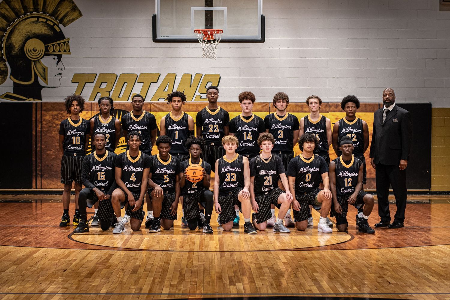 Millington Trojans boys basketball team formal group photo in school gymnasium.