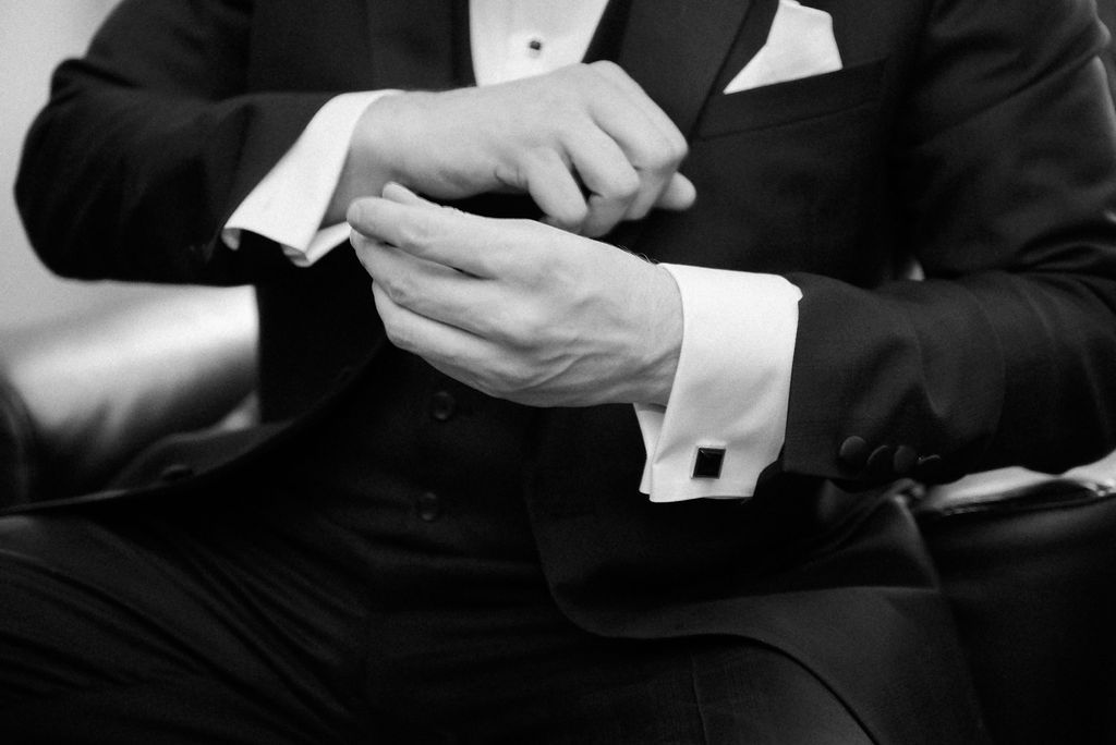 Close-up details of formal black tuxedos and white dress shirts at a wedding.