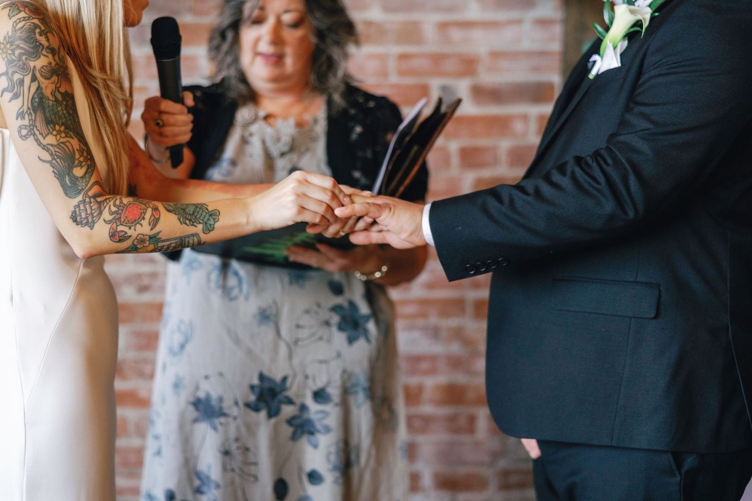 A couple exchanges vows during an intimate brick-walled wedding ceremony.