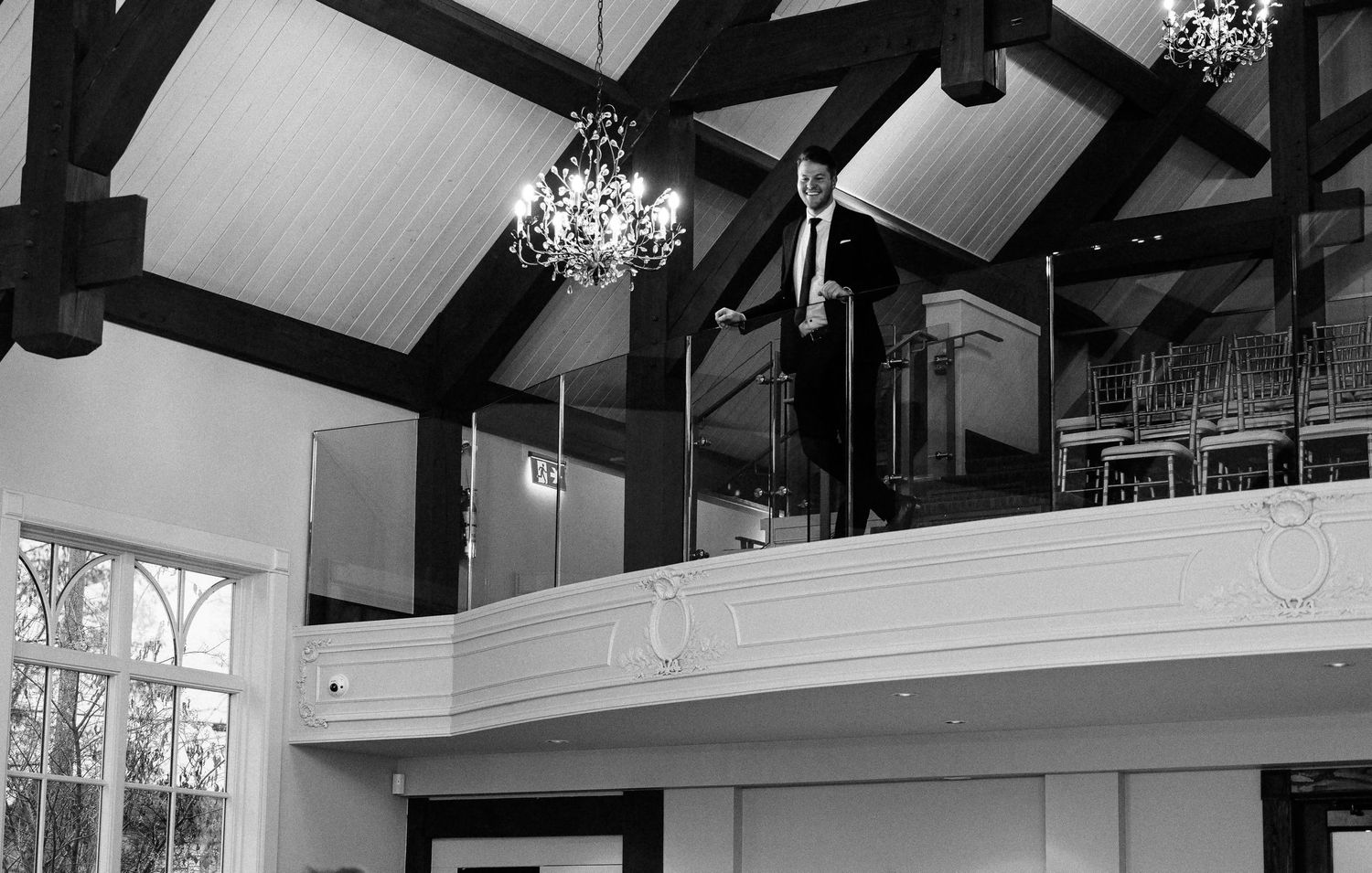 Modern wedding venue interior features exposed beams and elegant chandeliers.