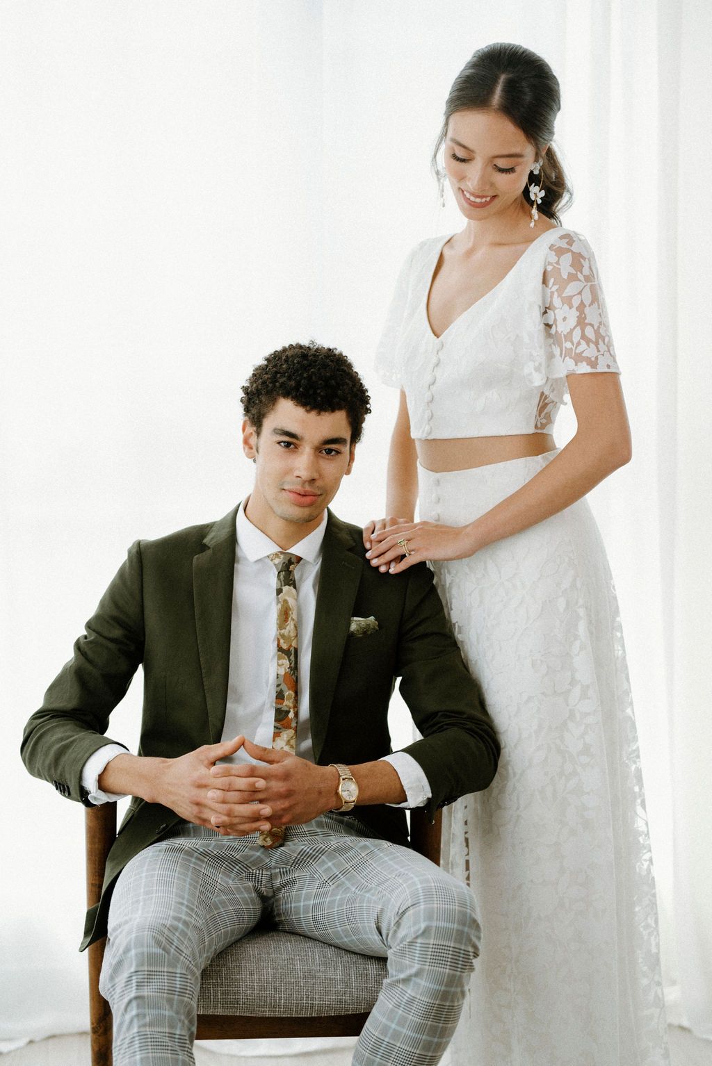 Modern wedding couple portrait with bride in two-piece lace dress and groom in plaid suit.