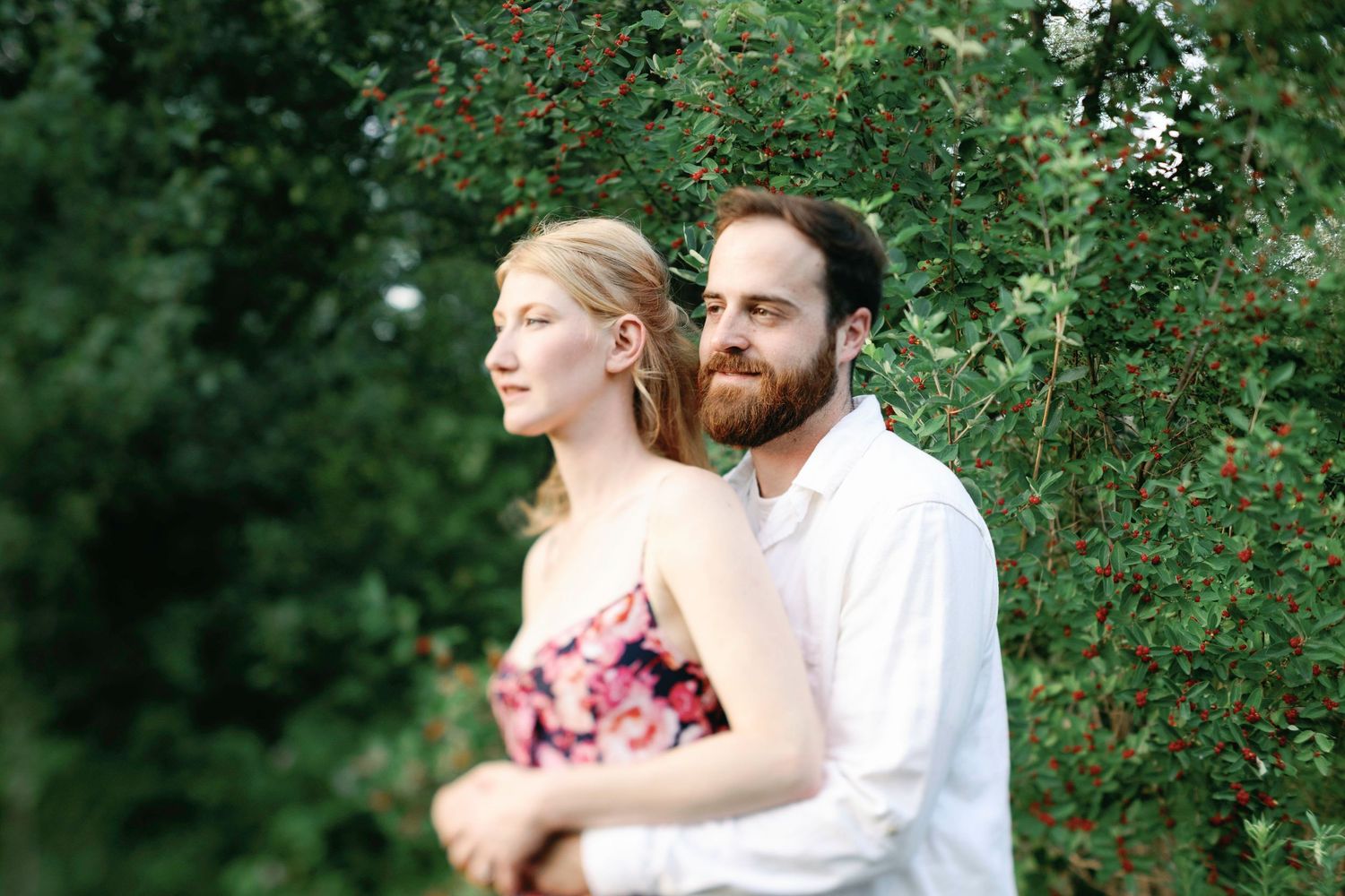 Romantic couple pose among flowering bushes in garden setting.