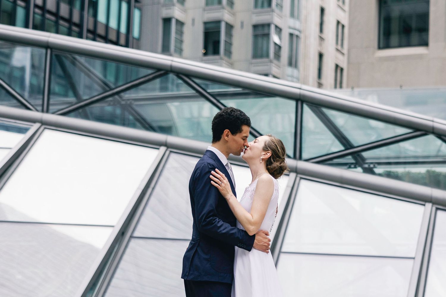 A romantic wedding moment captured against modern glass architecture.