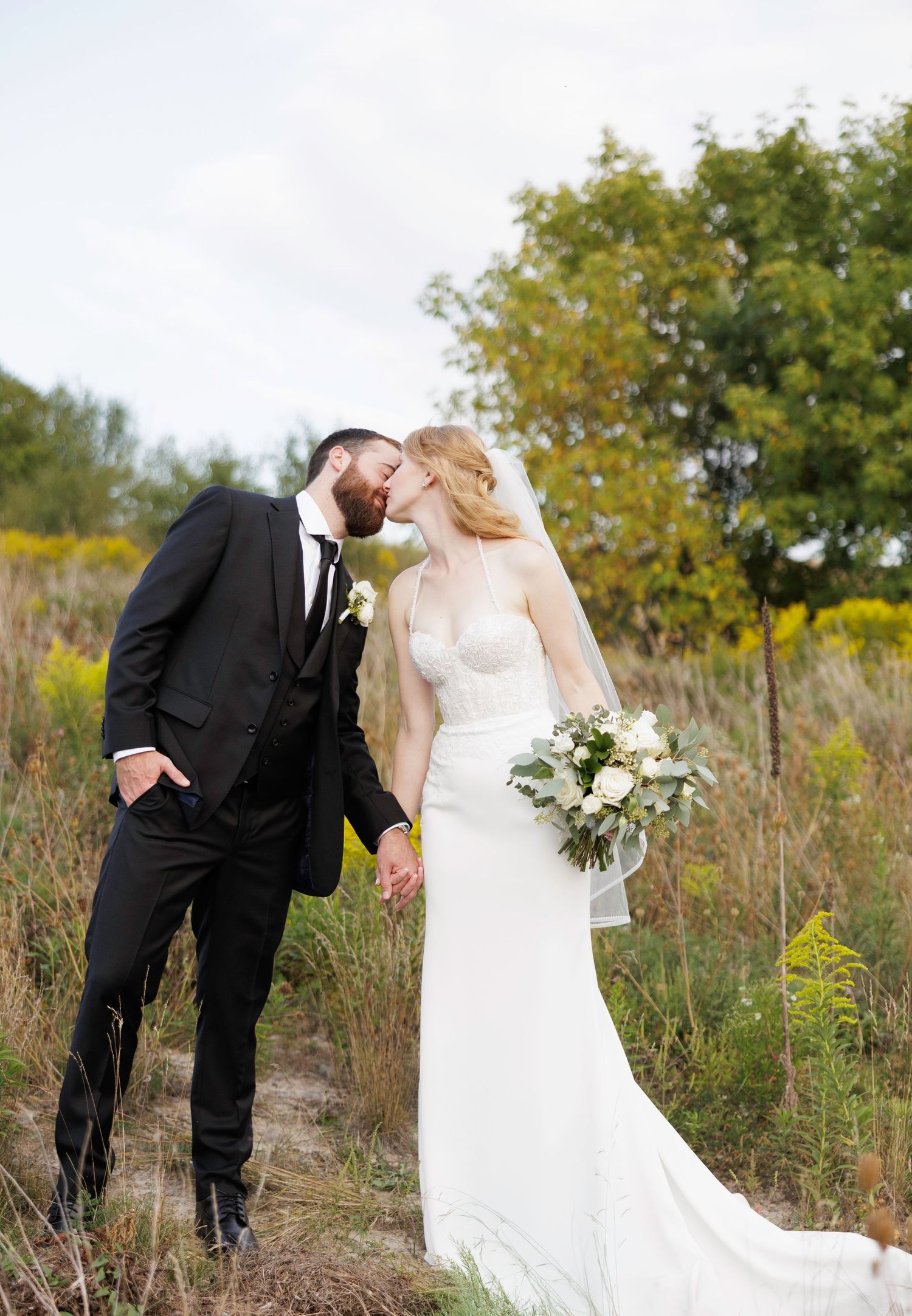 Romantic wedding portraits captured in a natural setting with yellow wildflowers and autumn foliage.