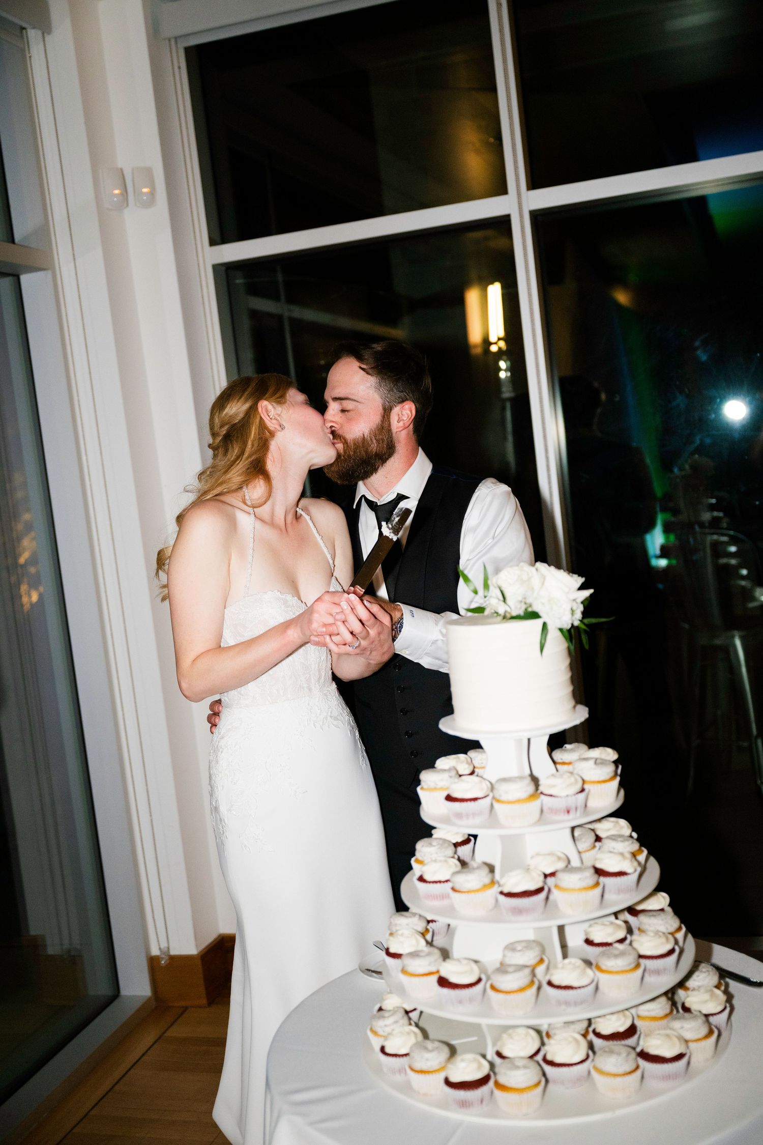 A tiered display of cupcakes at a wedding reception decorated in white and cream colors.