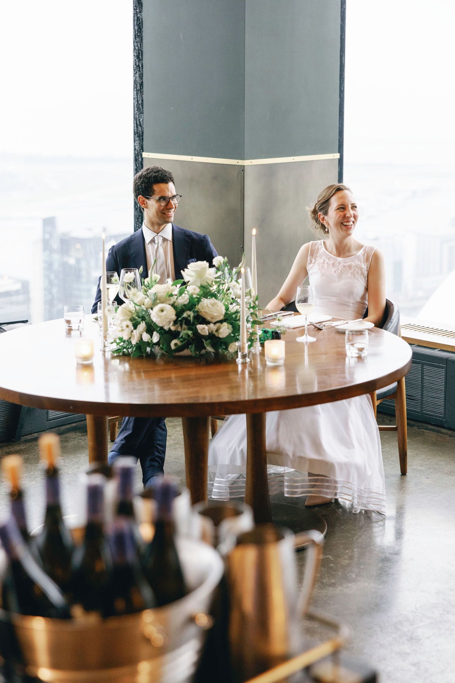 Wedding reception setup with round tables, floral centerpieces and champagne buckets.