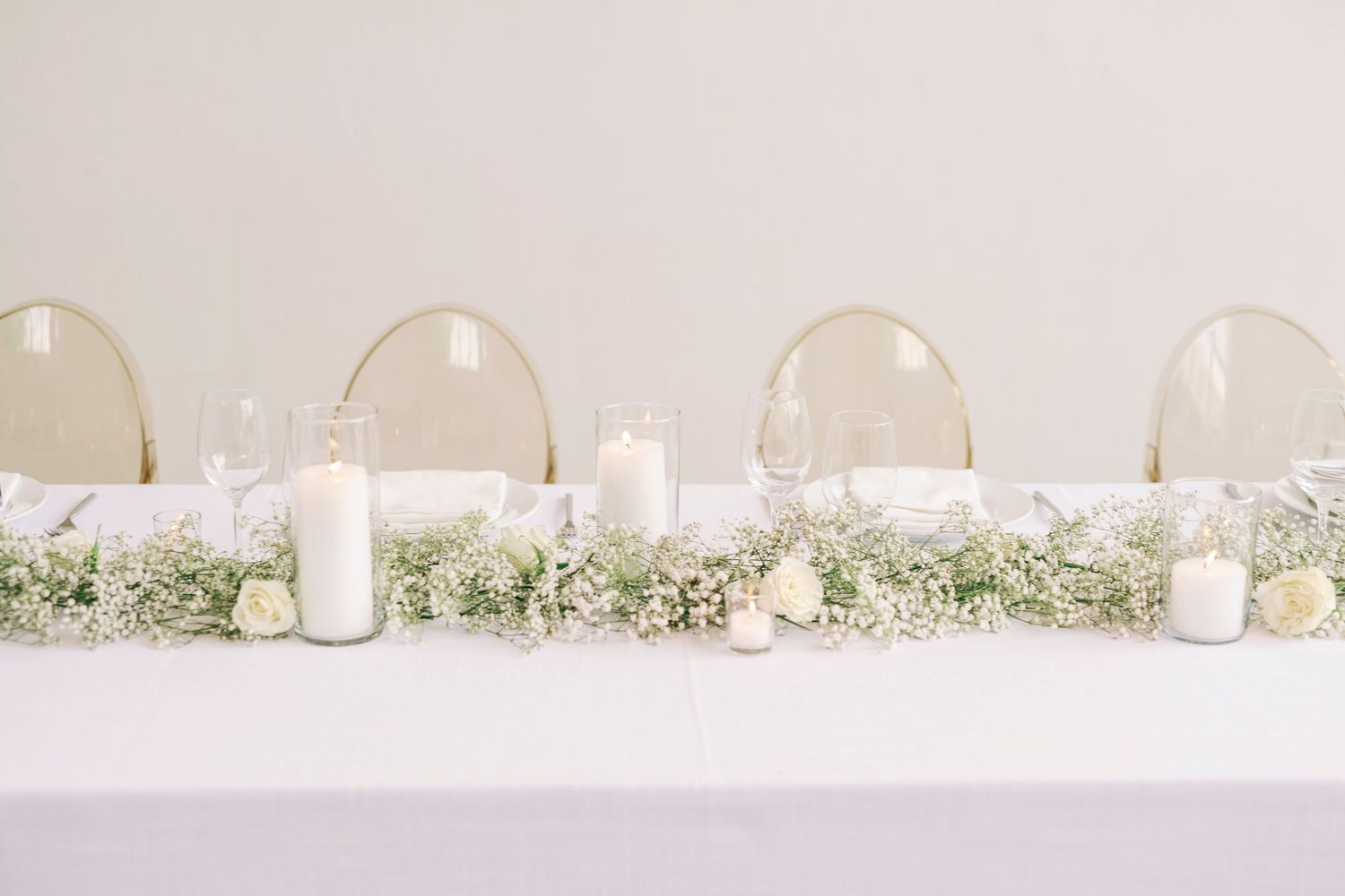 Elegant white reception table settings with ghost chairs and minimal decor.