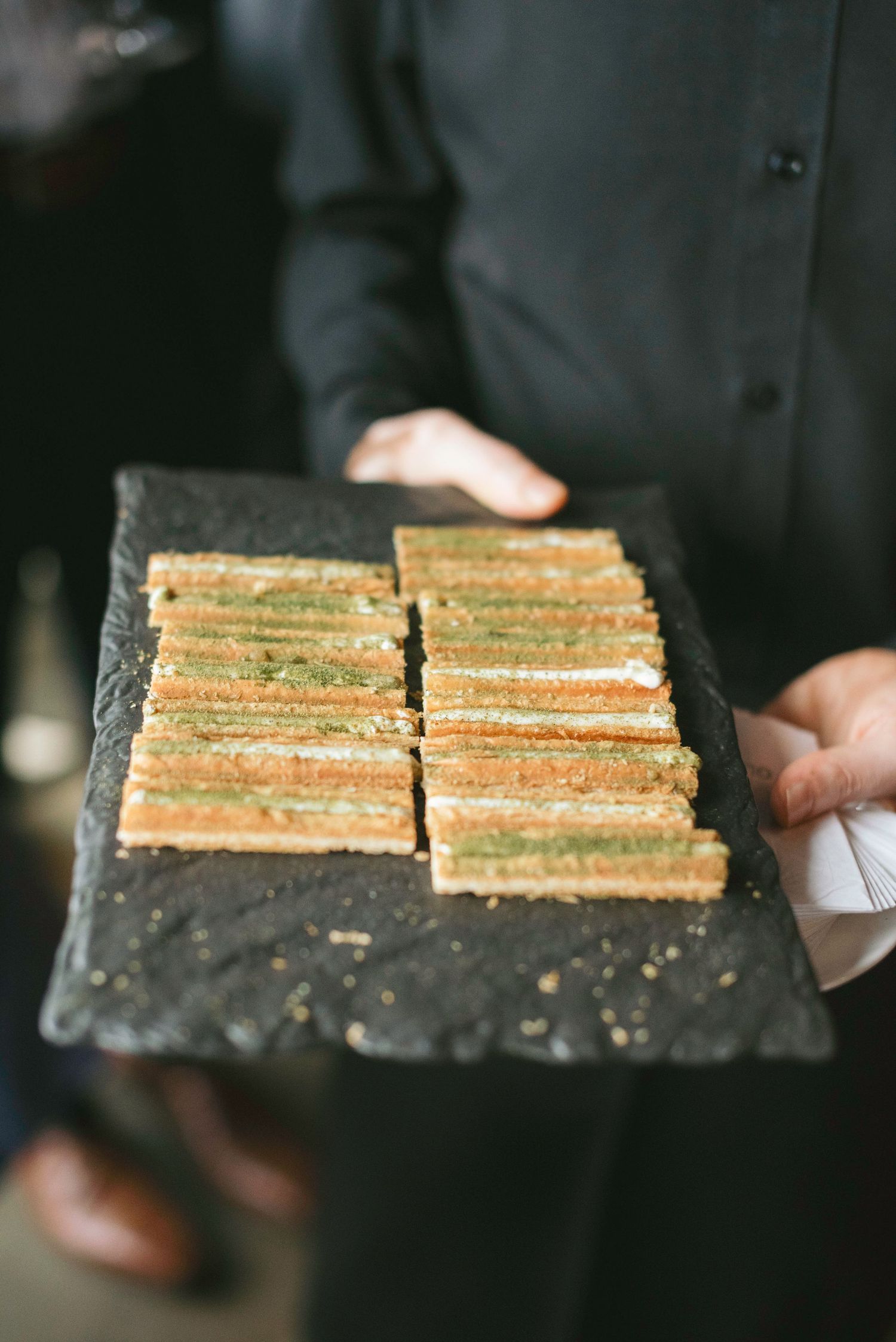 Elegant finger sandwiches arranged in rows on a dark slate serving platter.
