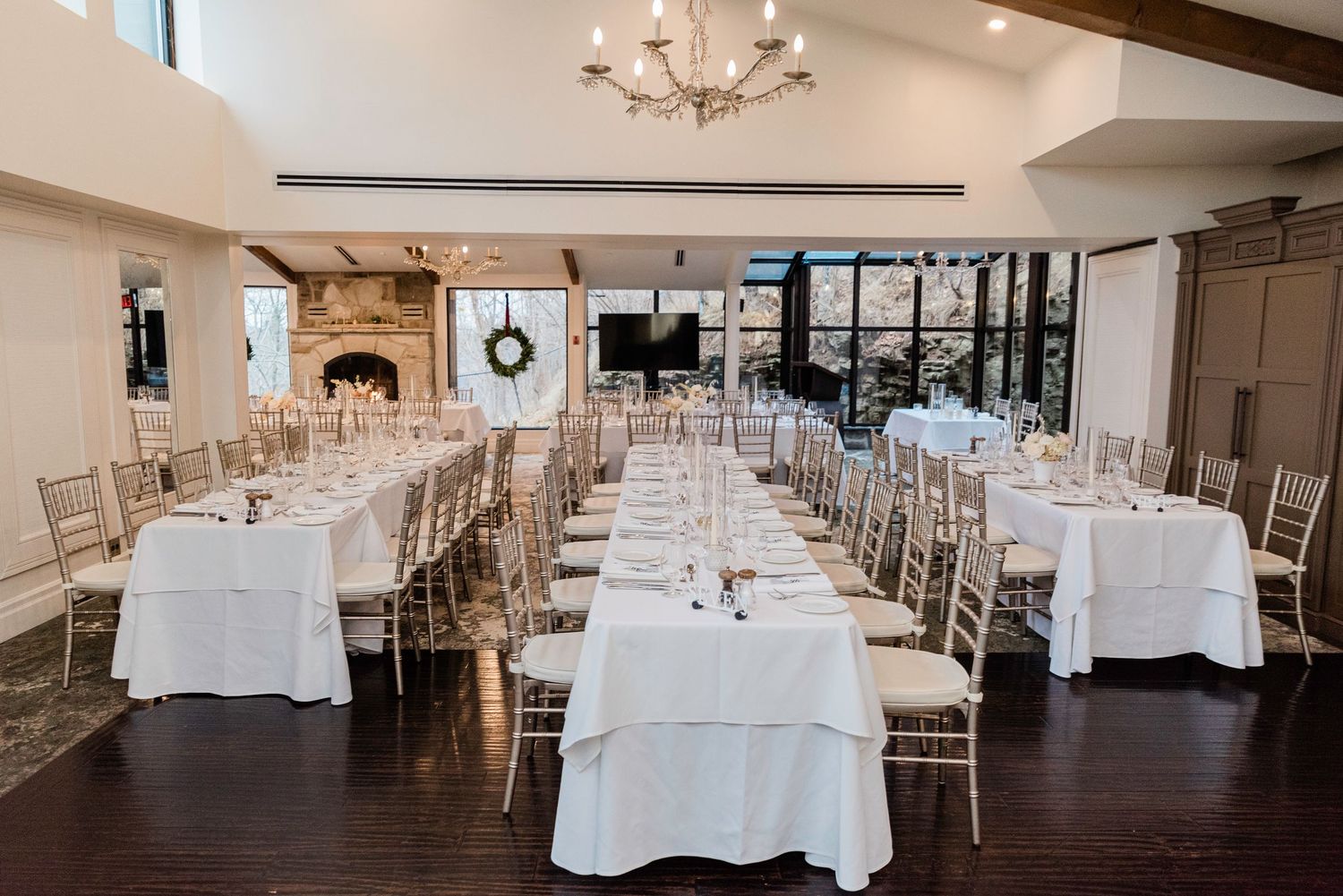 Reception hall set with round tables covered in white linens and elegant place settings.