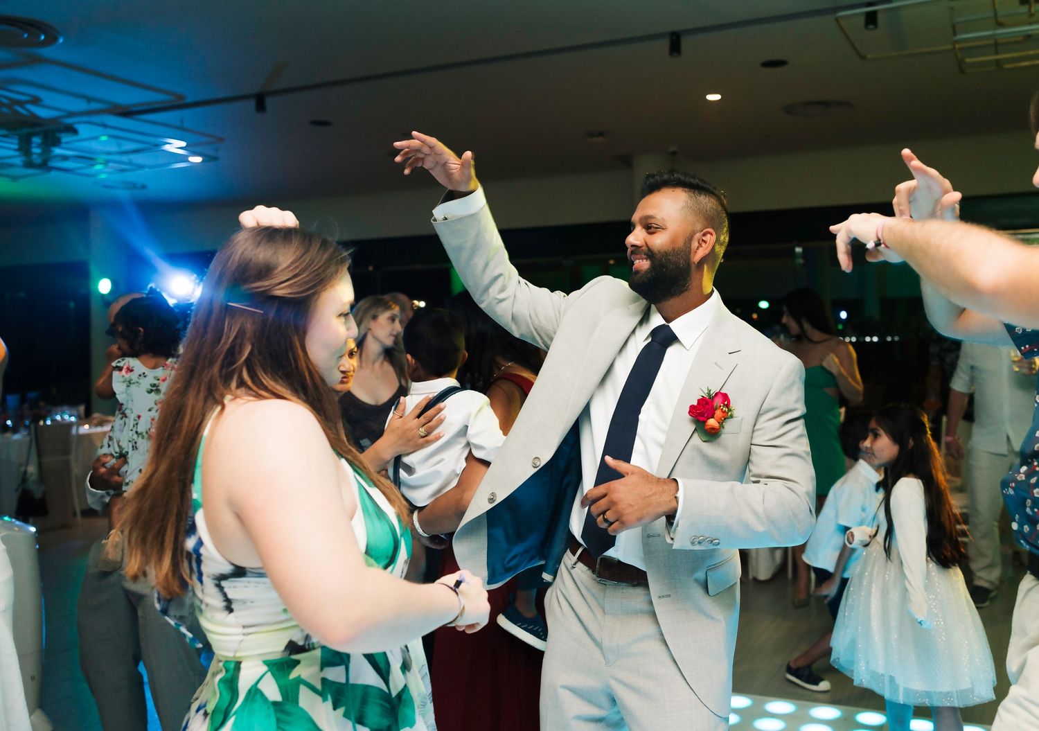 Wedding guests dance together on a glowing LED dance floor at an evening reception celebration.