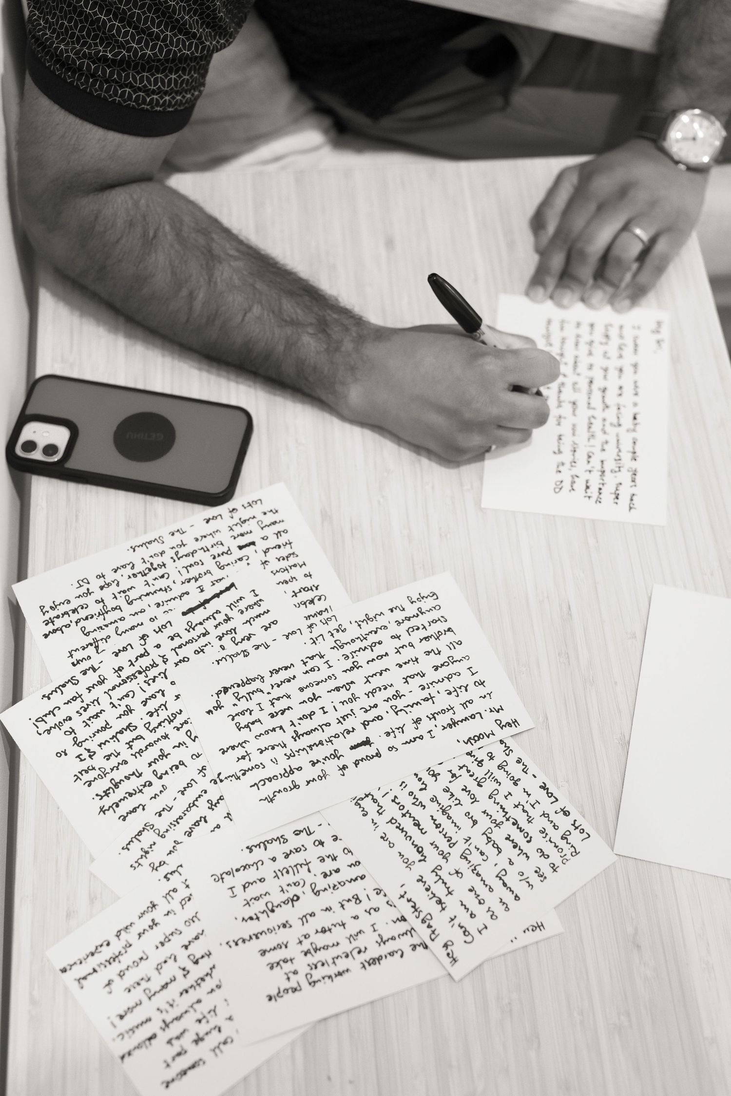 Handwritten wedding vows spread across a white surface with a phone visible in the corner.
