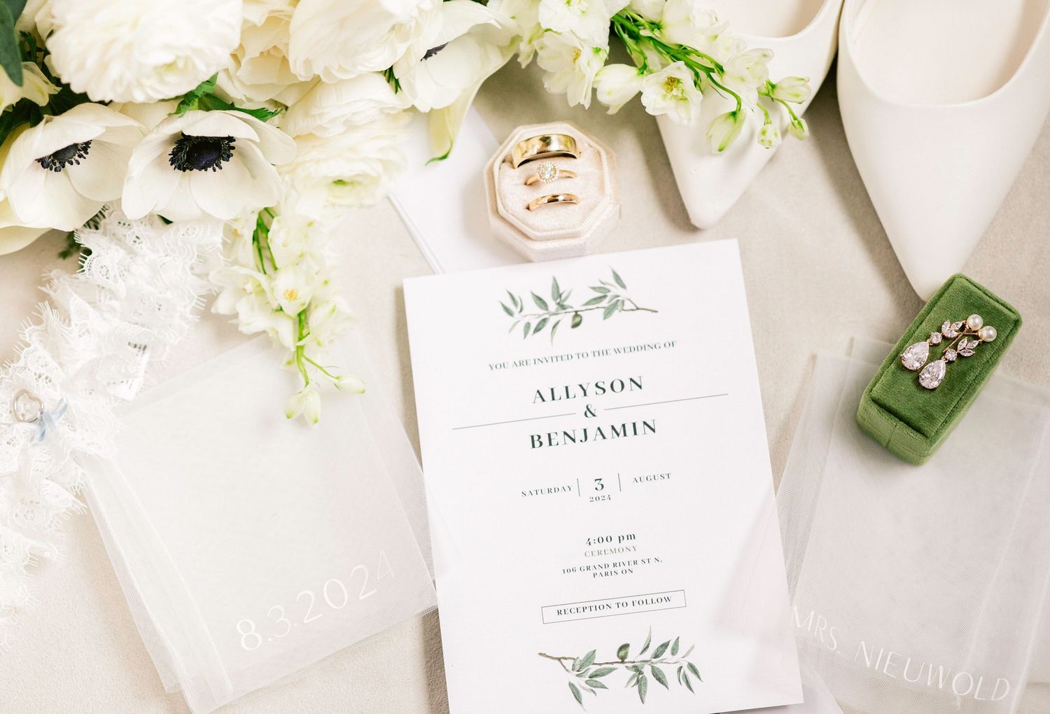 Elegant wedding stationery with white floral arrangements and delicate greenery on a light neutral background.
