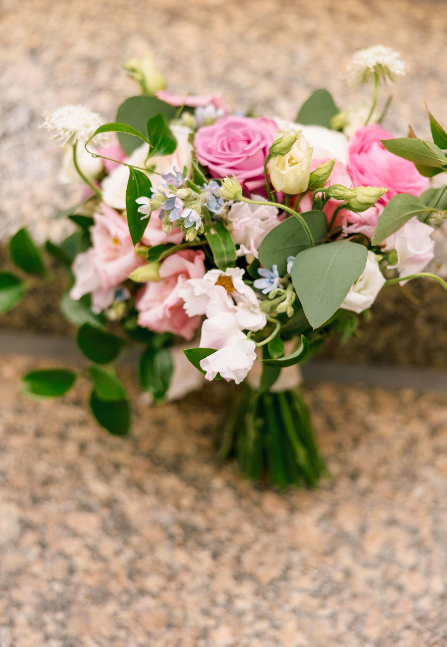 Delicate pink and white floral arrangement with roses and eucalyptus leaves.