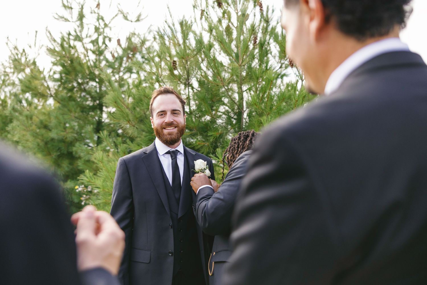 A group of formally dressed people gathered outdoors in a garden setting during a social event.