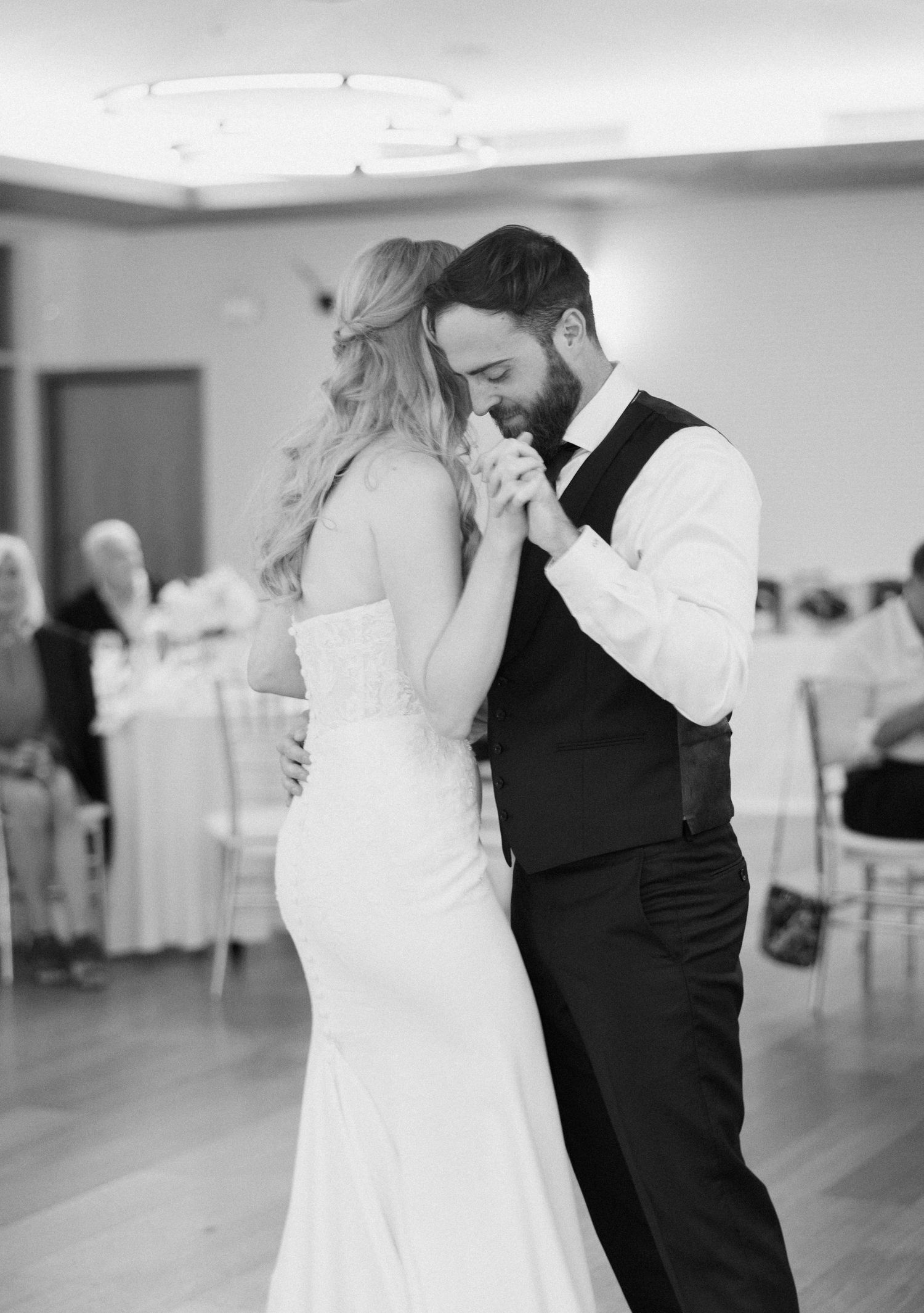 A couple shares an intimate first dance moment in a bright reception hall.