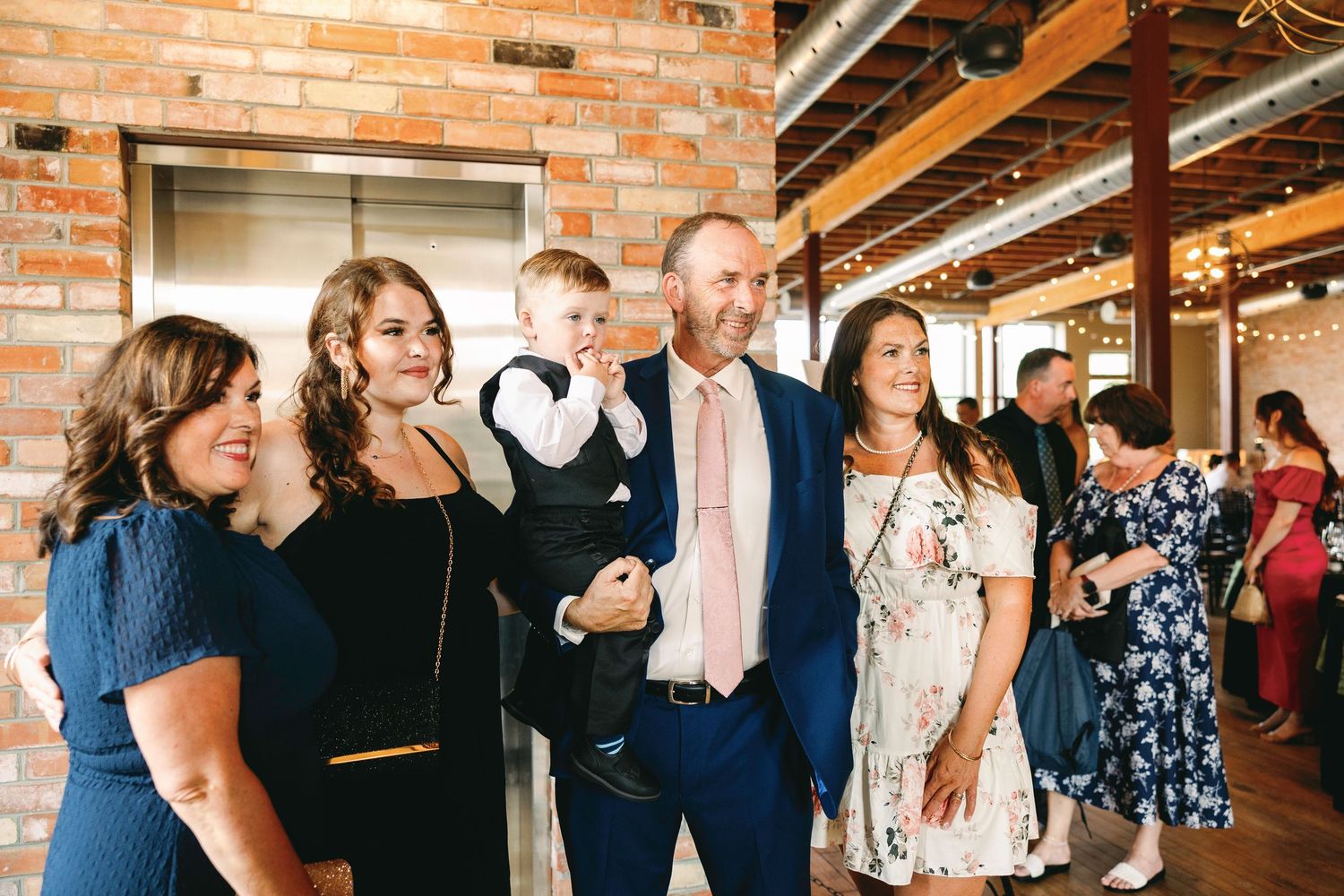 Wedding guests mingle and socialize at a rustic brick-walled venue during a reception celebration.