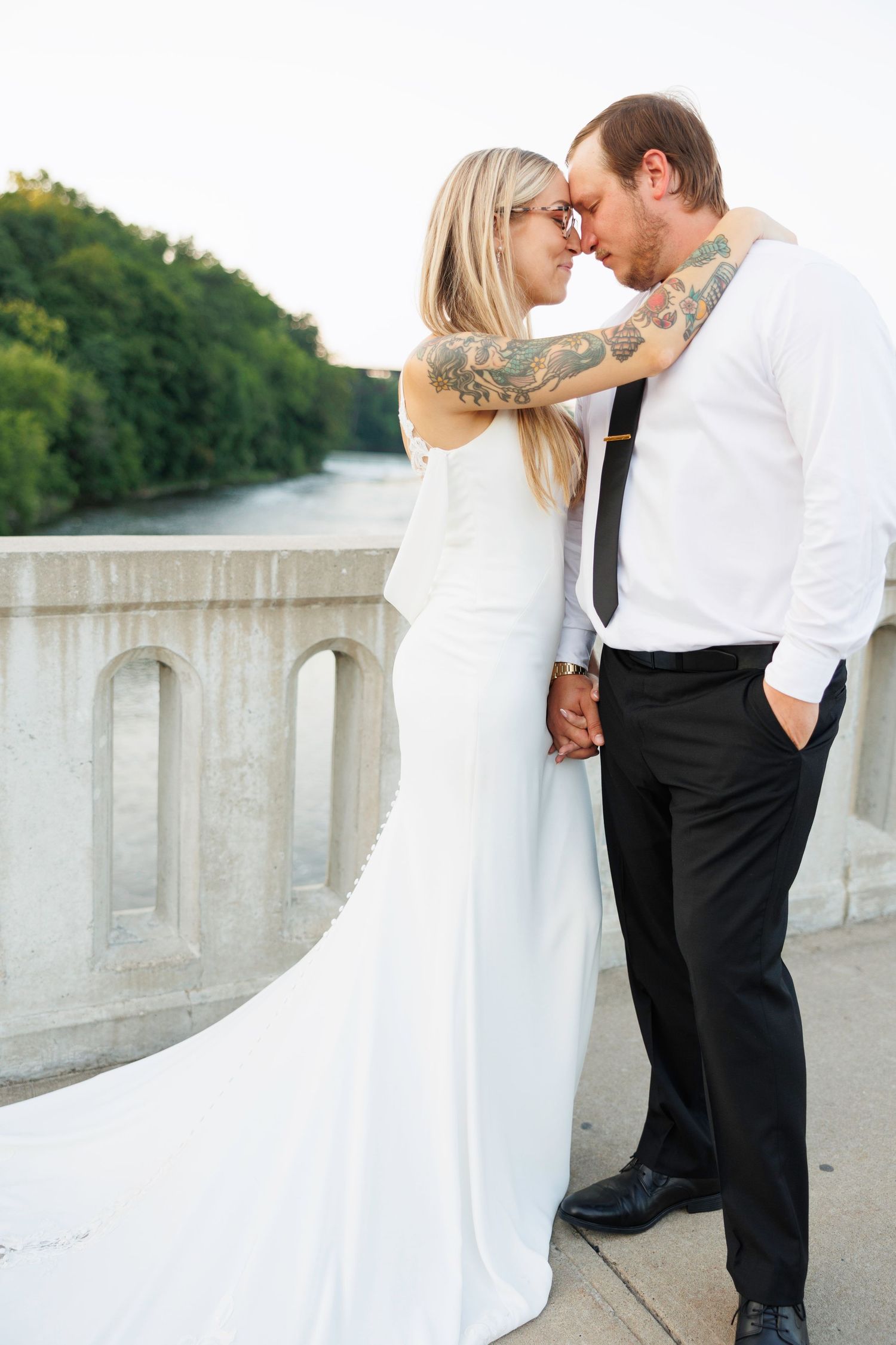 A romantic wedding photo series showing a couple in formal attire embracing on a stone bridge during their special day.