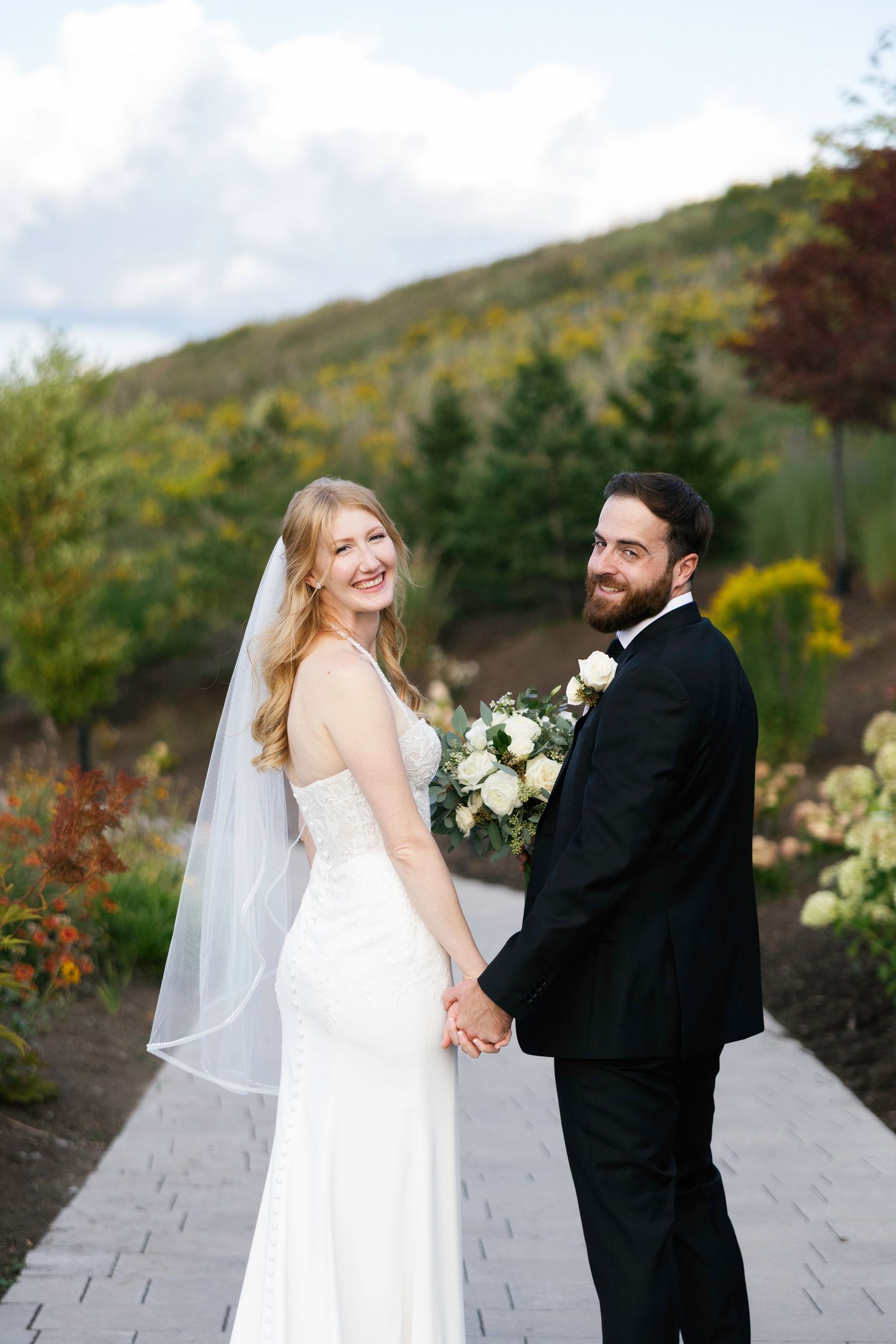 A scenic outdoor wedding portrait with mountain landscape in the background.
