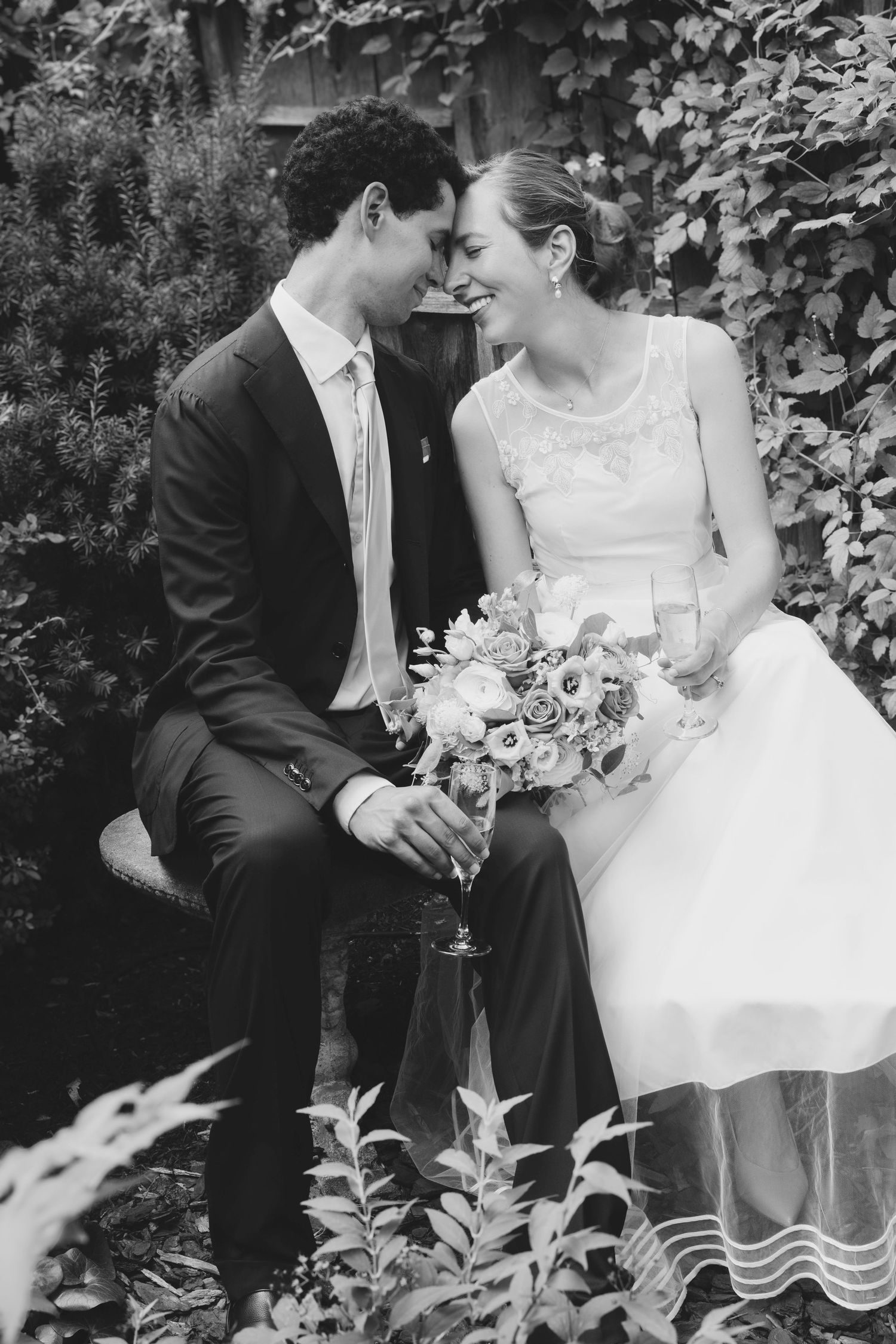 Black and white wedding photos of a couple sitting together in a garden setting.