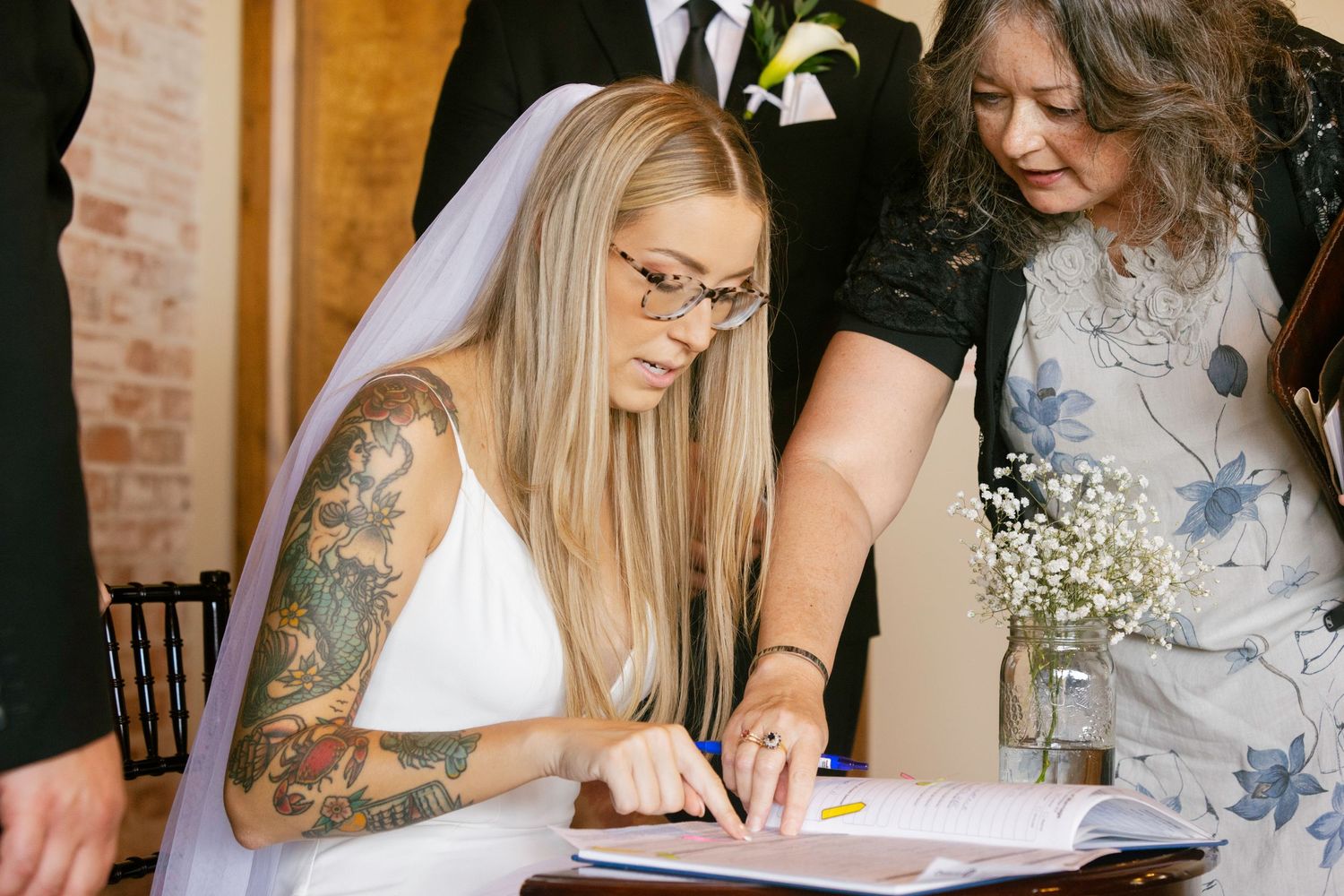 A series of photos showing people signing documents at a formal event with flowers and brick wall backgrounds.