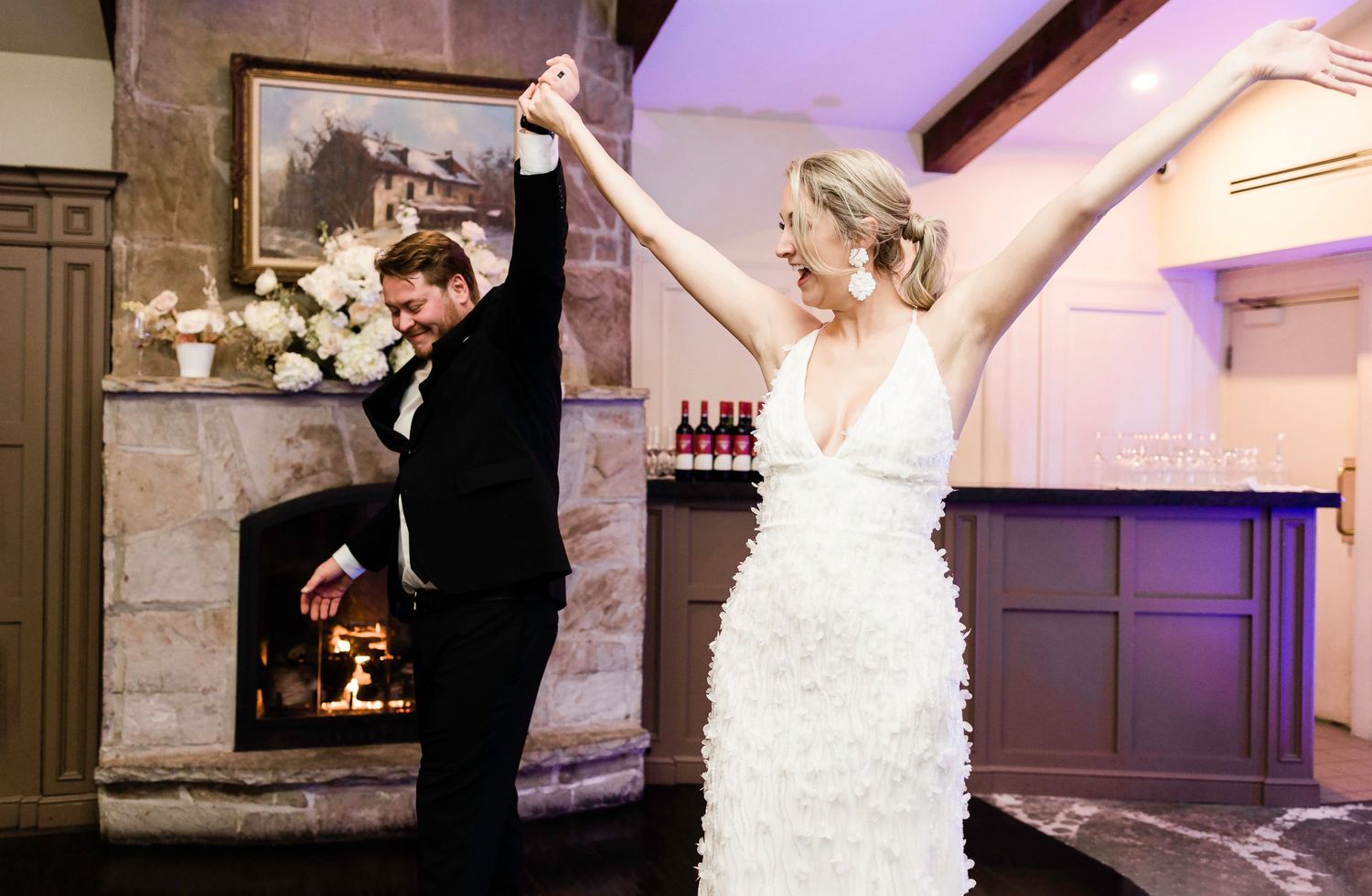 Couple dances at wedding reception with purple uplighting and stone wall details.