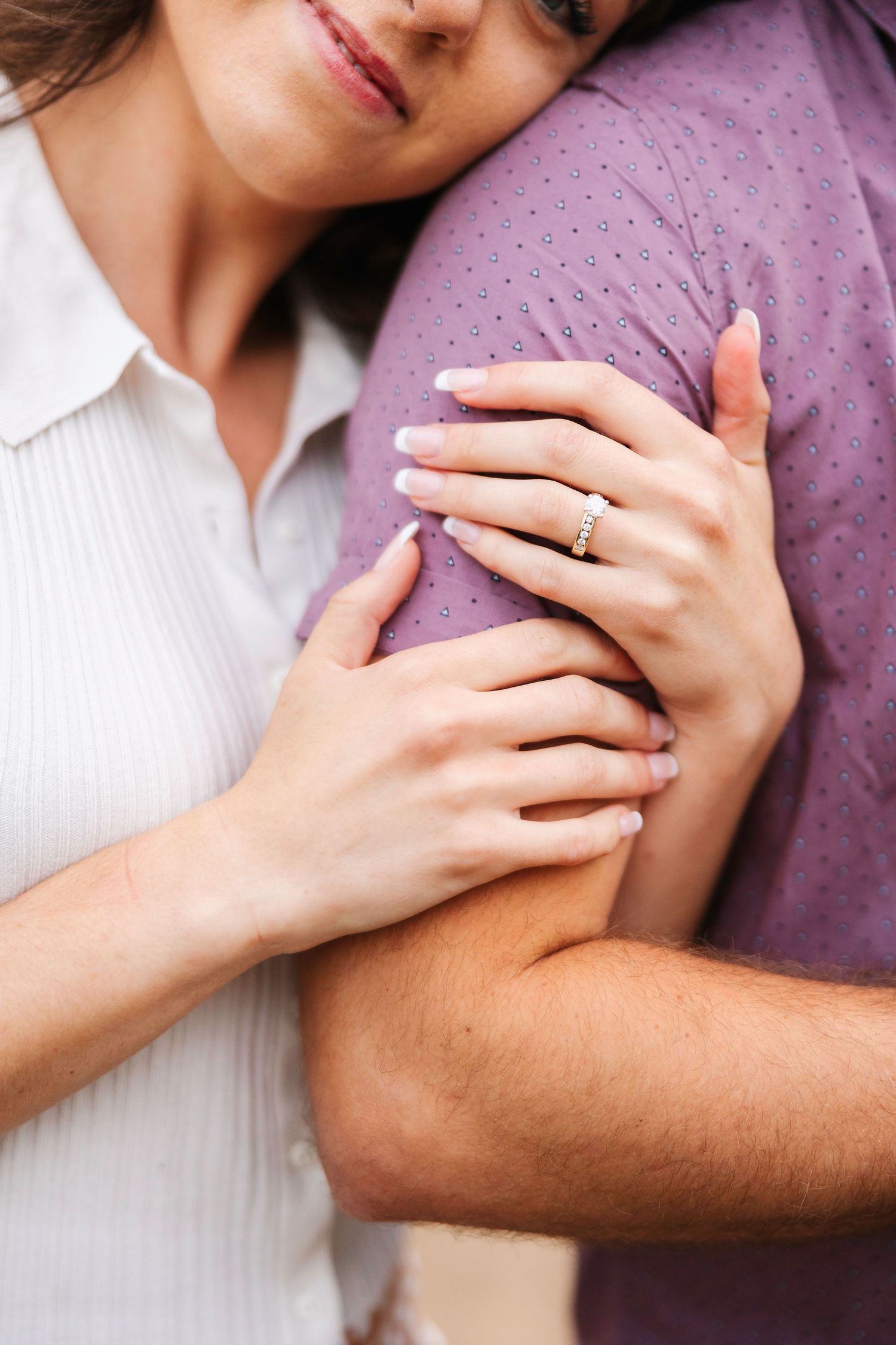 Close-up shot of hands with engagement ring showing tender moment.