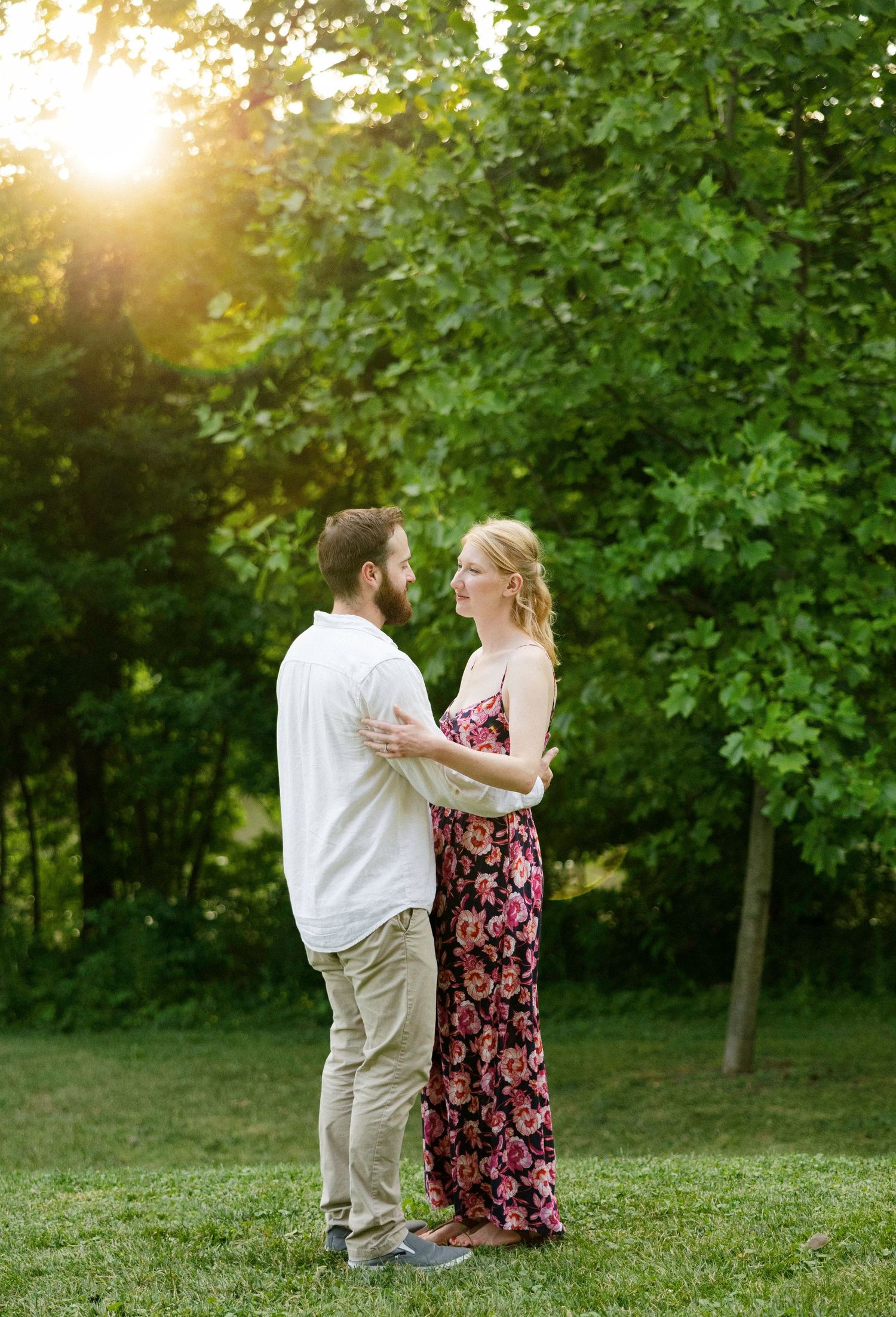Couple sharing tender moment at sunset in lush green park.