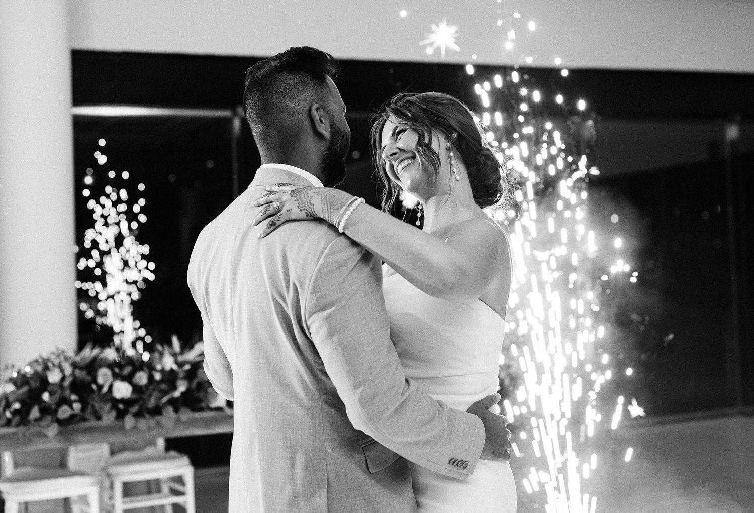 A series of romantic first dance moments at a wedding reception with sparklers creating magical light effects in the background.