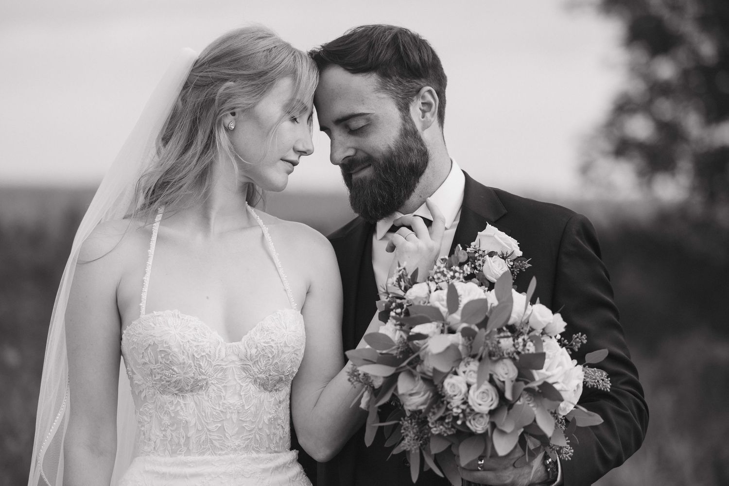 A tender wedding moment captured in black and white with a beautiful floral bouquet.