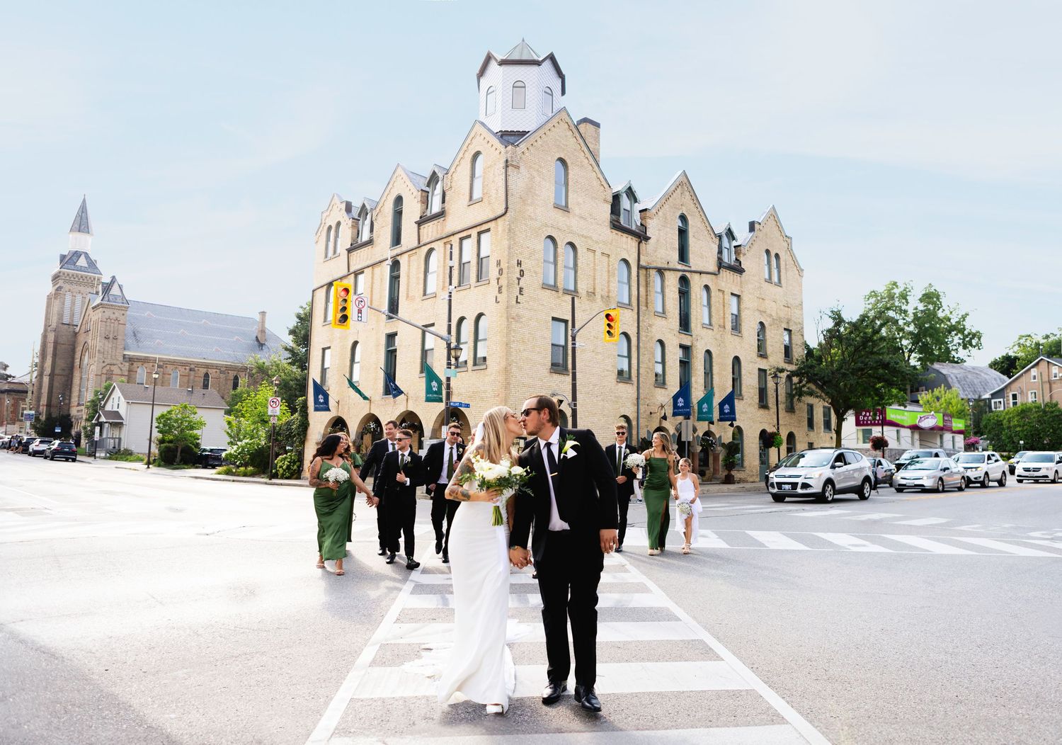 Wedding party walks together in a line across an urban crosswalk on an overcast day.